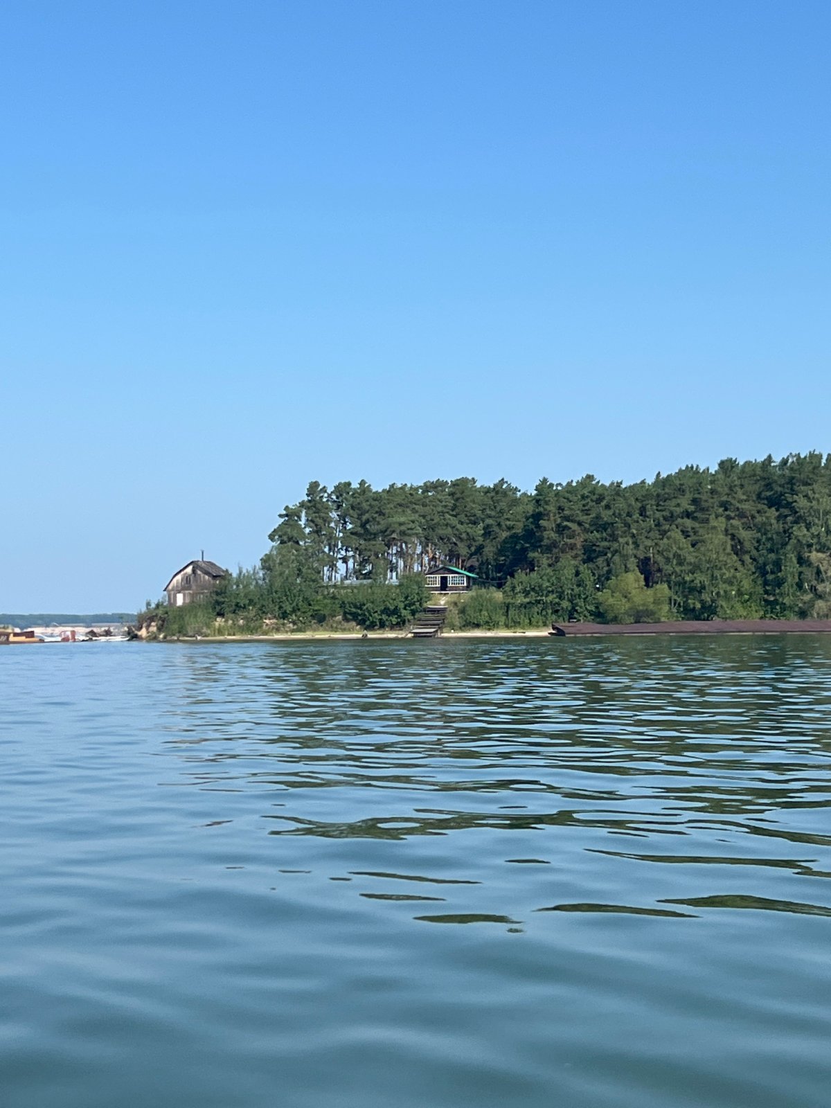 Calm Russian waterway, beached barge, and a motorboat out on the water