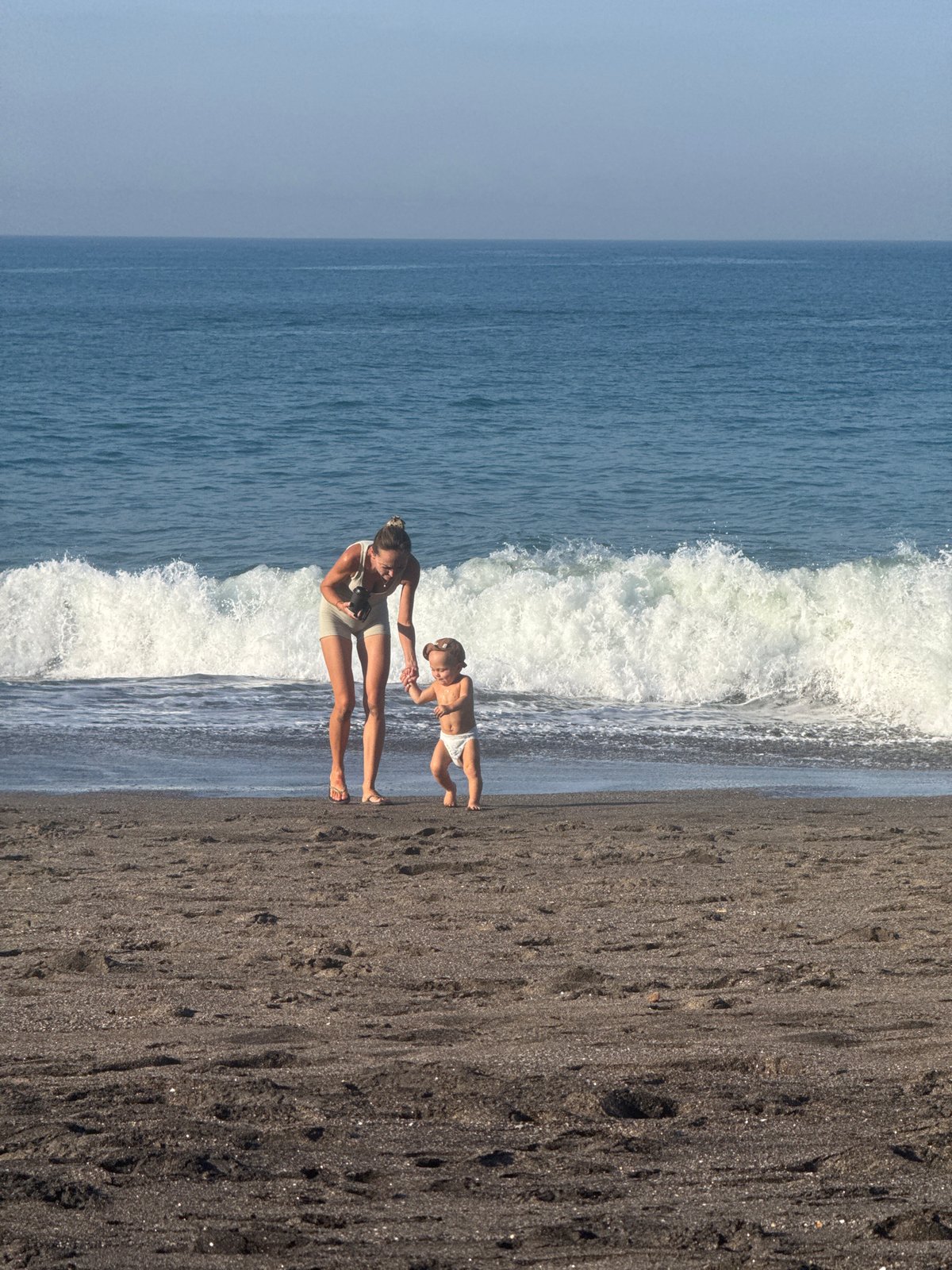 Woman and child enjoy early morning beach visit in Mengwi