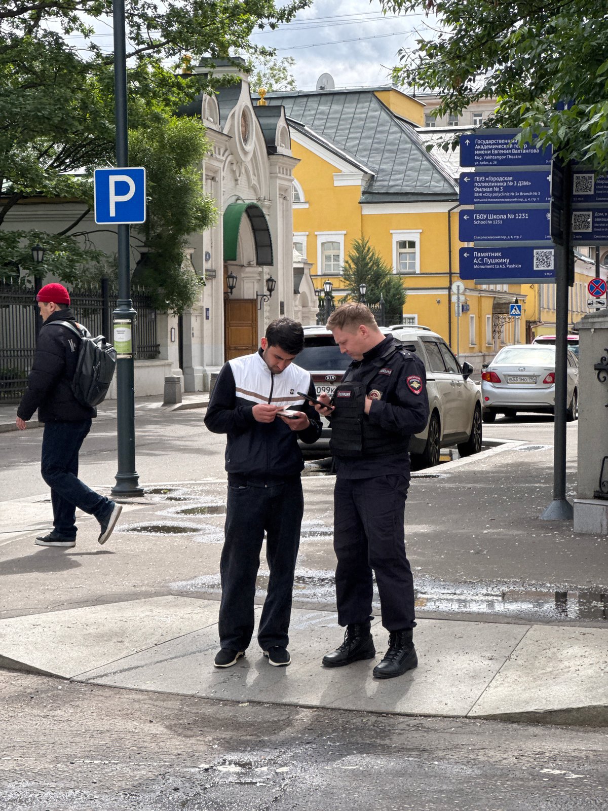 Police officer and civilian check phones on Moscow street