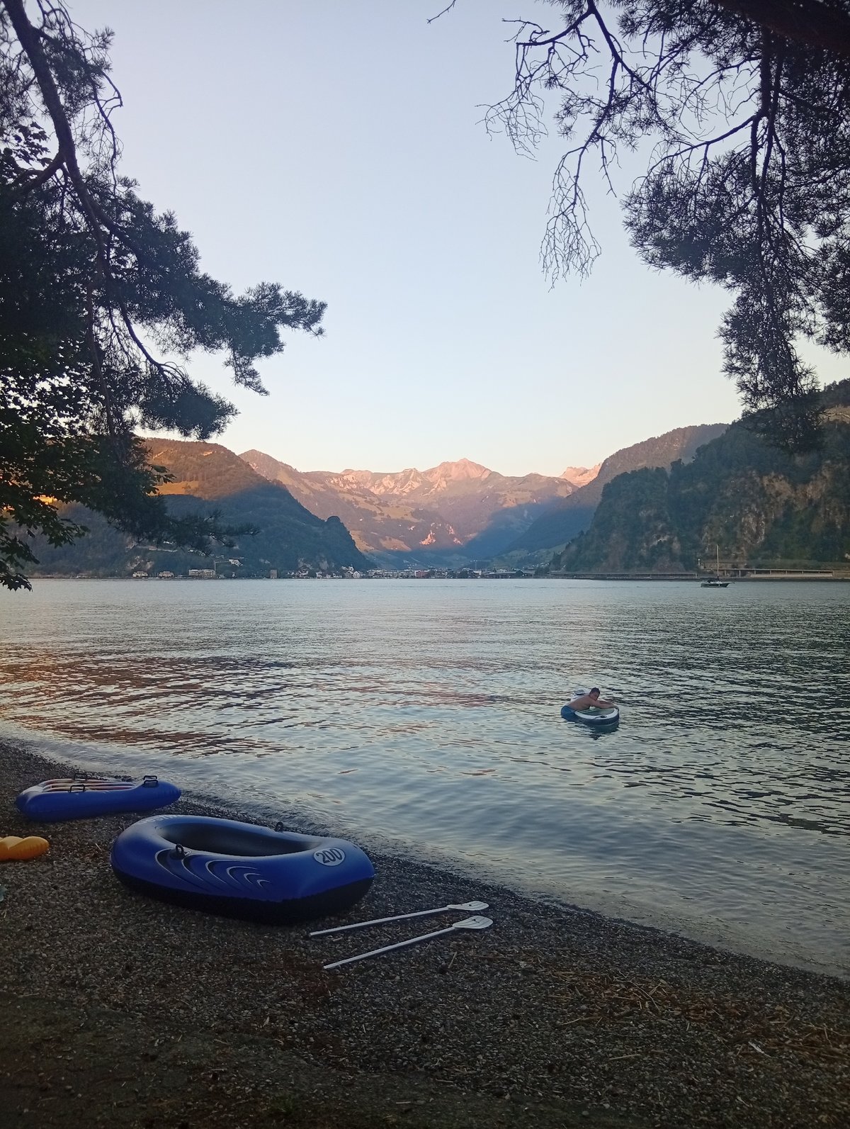 Inflatable boats resting on a Lake Lucerne pebble shore at dusk