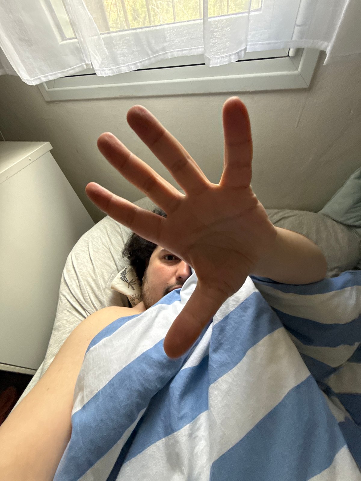 Person rests in bed with striped bedding in Jerusalem