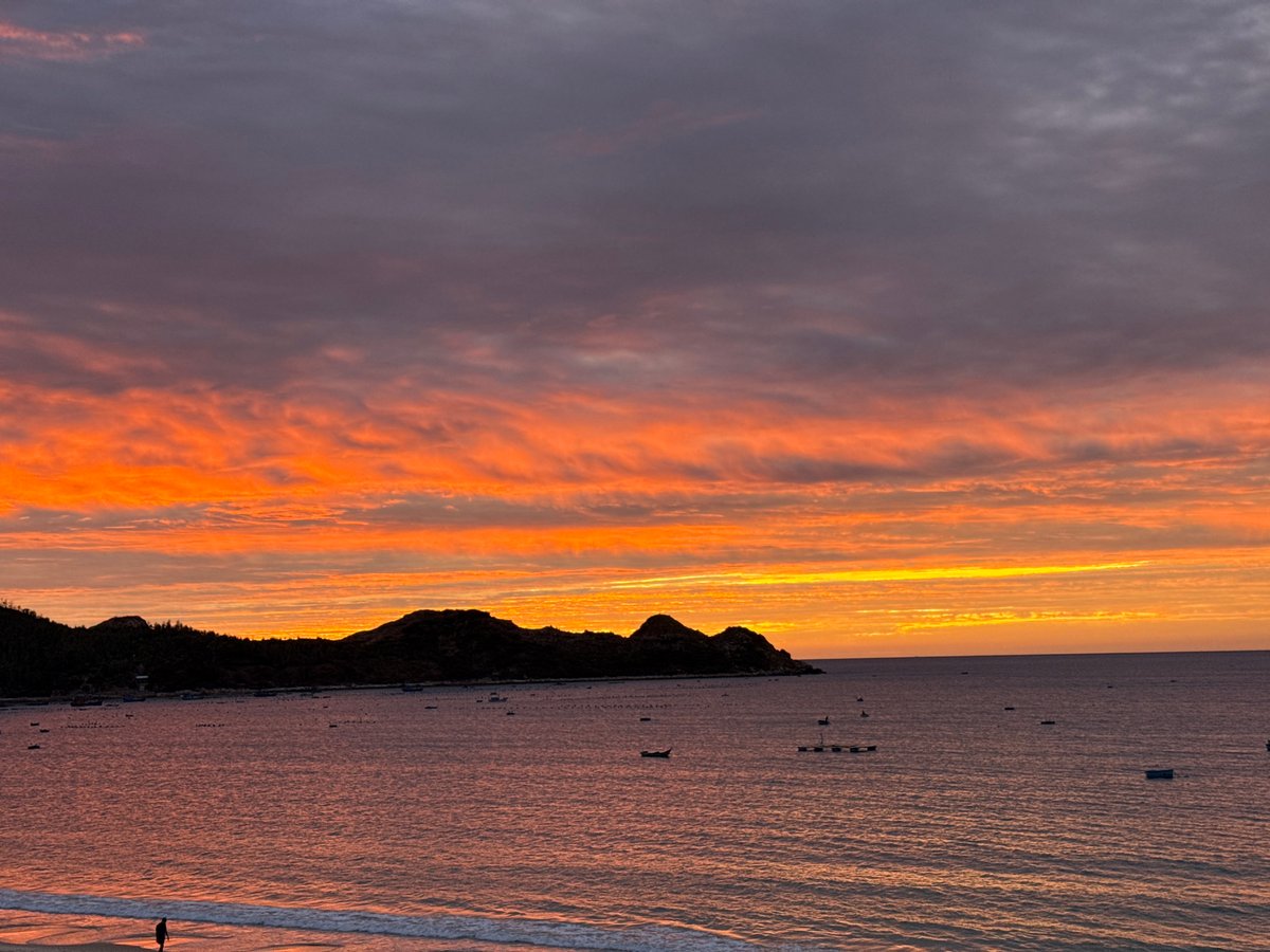 Sunset over a calm beach, sky shifting through vivid colors