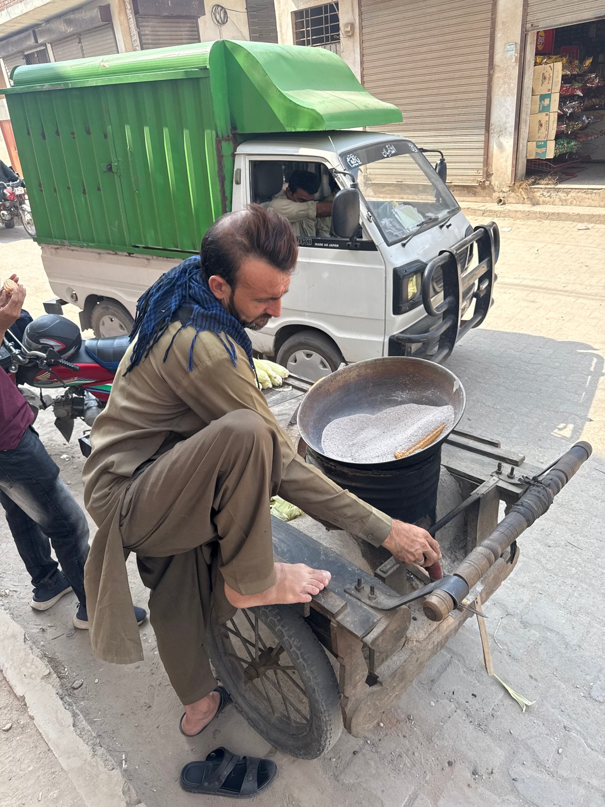 Street vendor roasts corn in sand-filled bowl in Multan