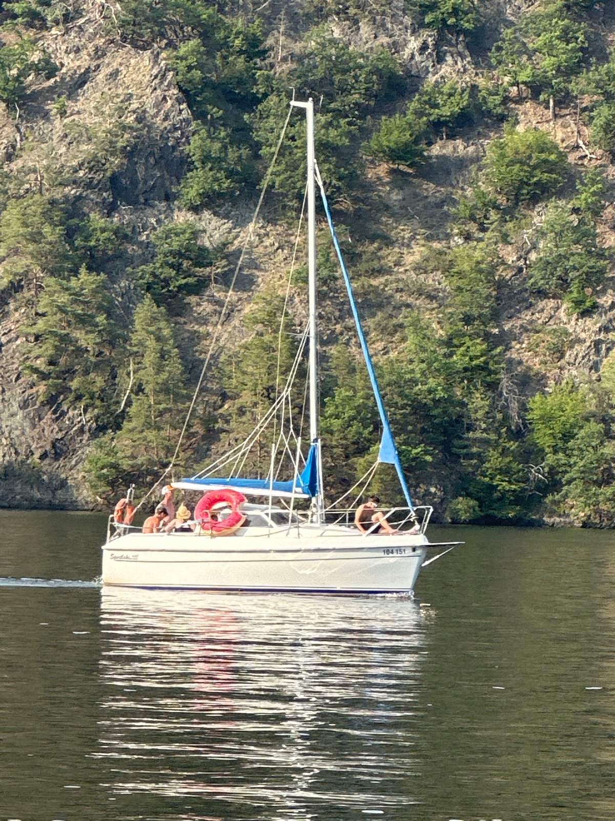 Lazy afternoon sail on a calm lake with forested banks