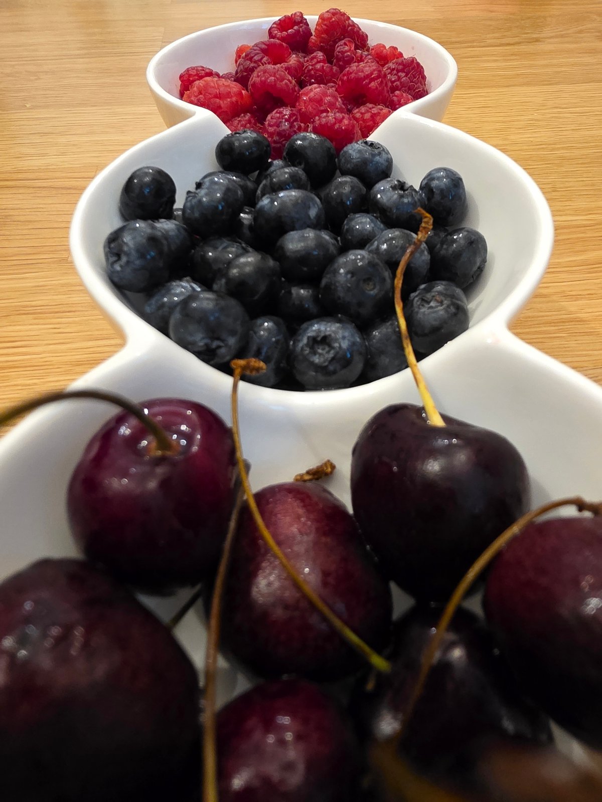 Fresh berries in ceramic bowls on a wooden surface
