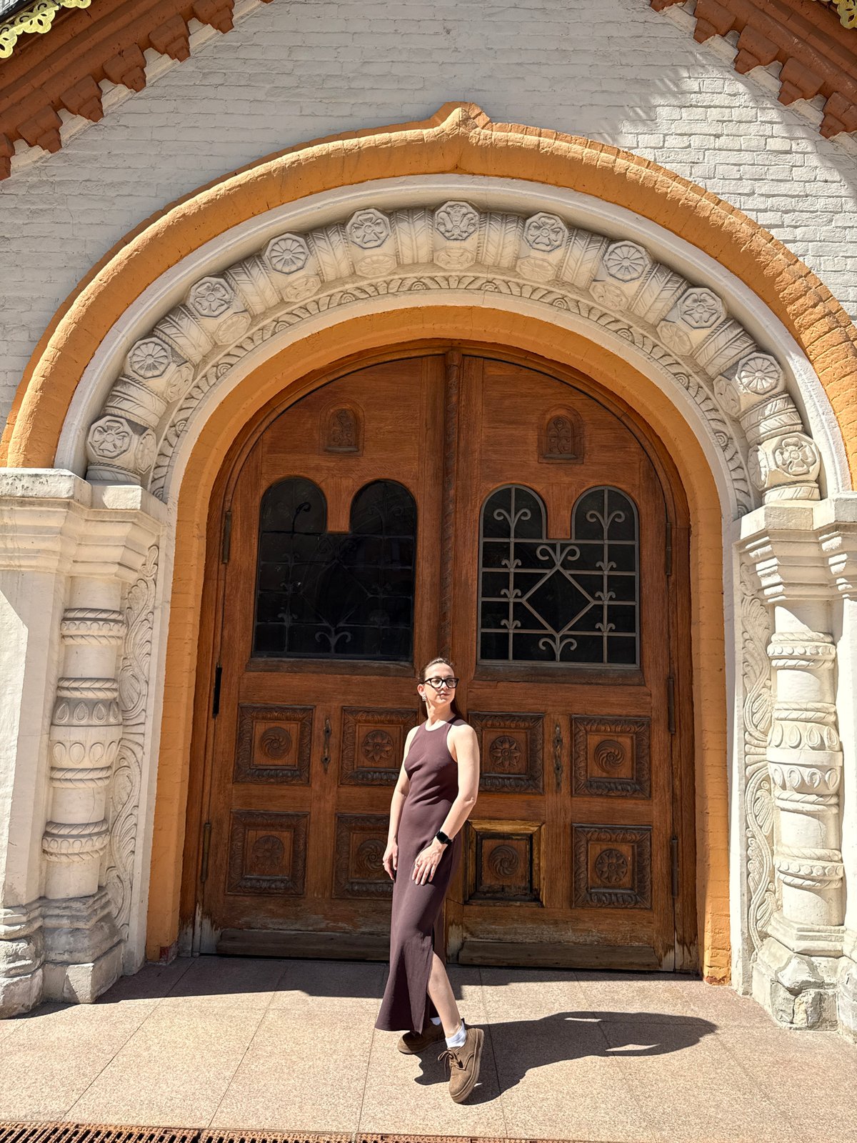 Woman in brown dress stands before ornate door in Moscow