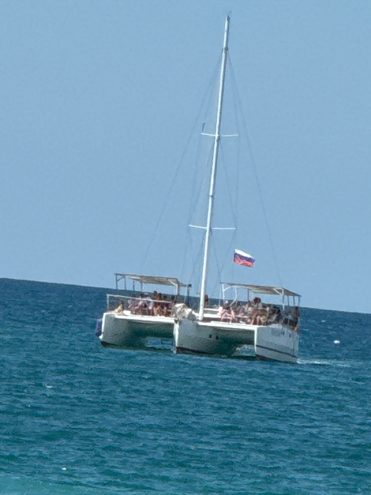 Sunny beach resort morning with café, loungers, and catamaran