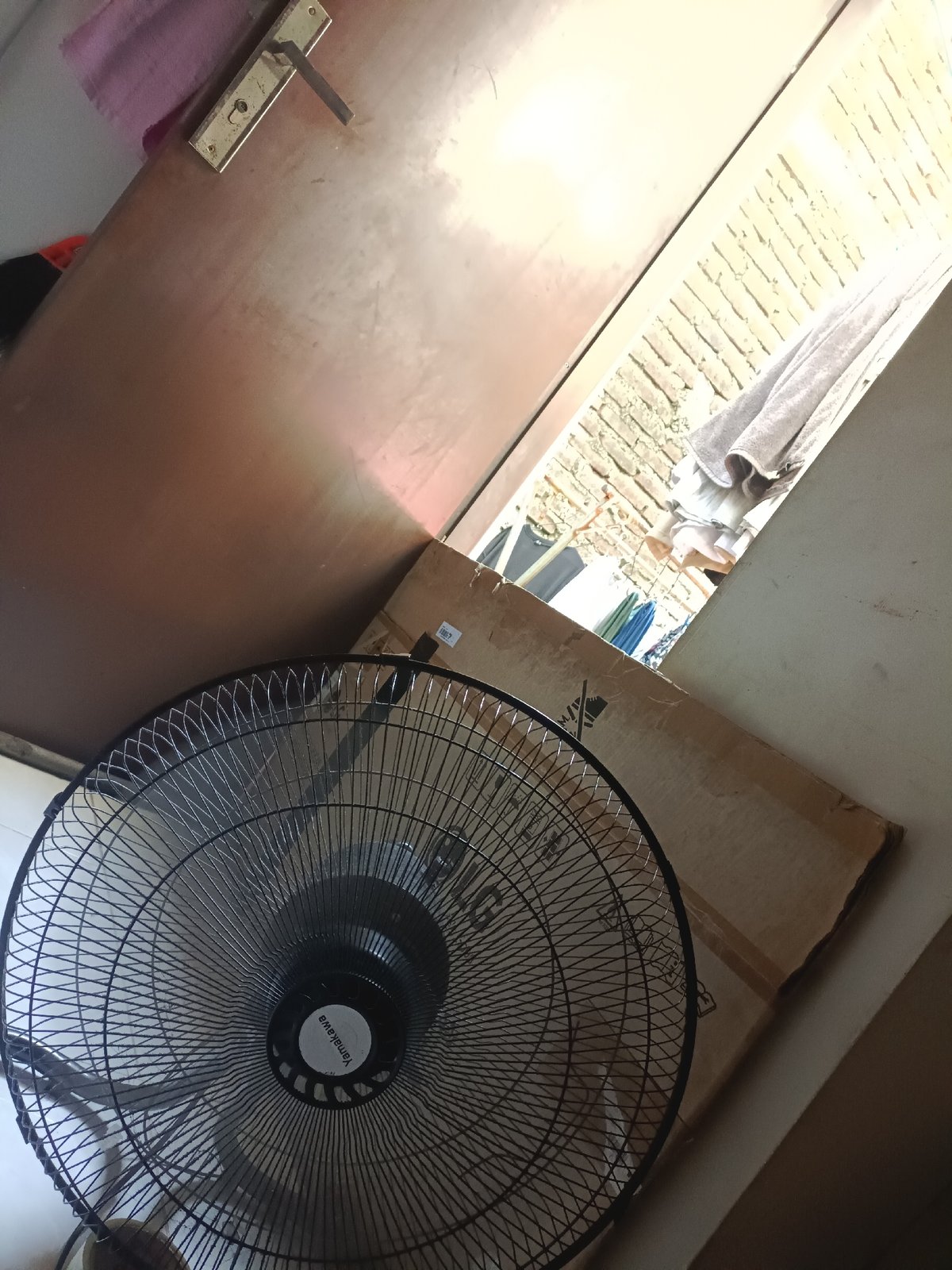 Indoor view through doorway features black standing fan