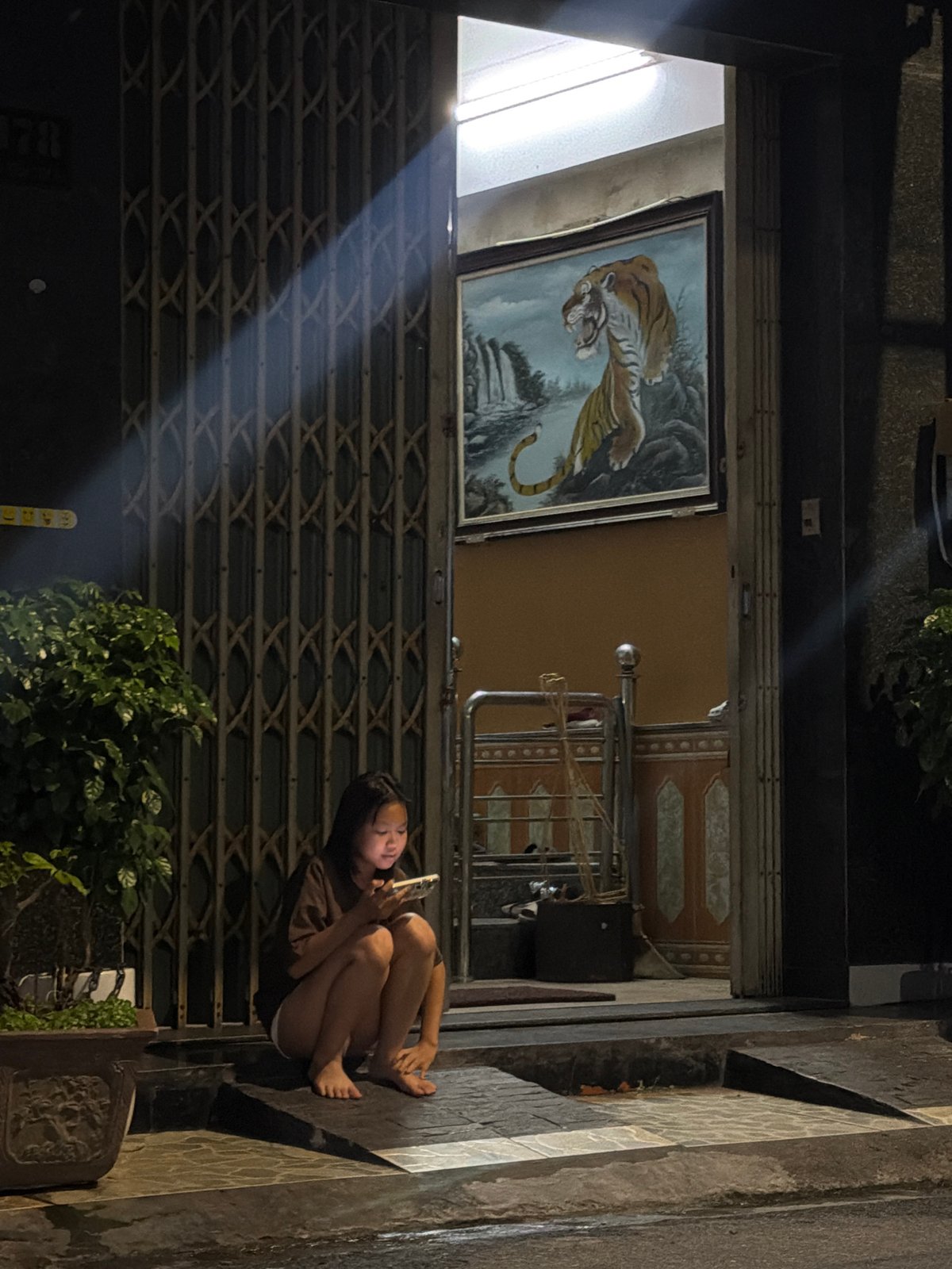 Person sits on sidewalk using phone in Đà Nẵng