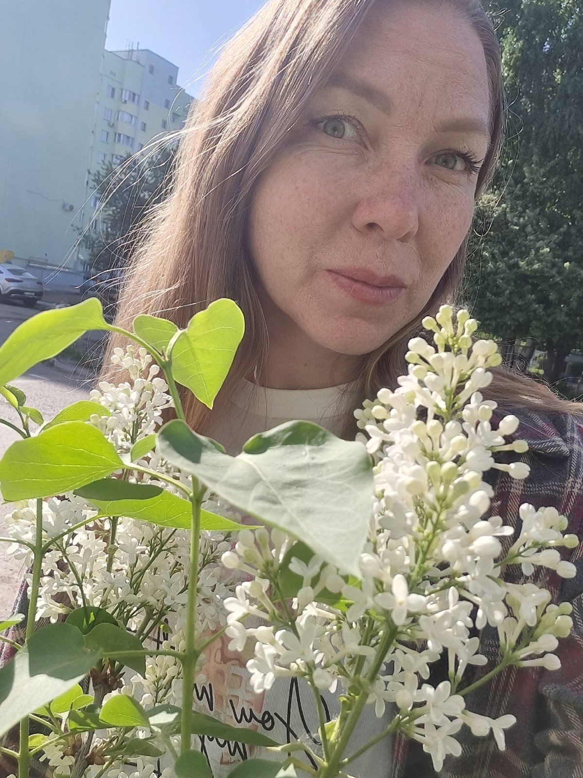 Woman poses with white lilac bouquet in Chaikovsky