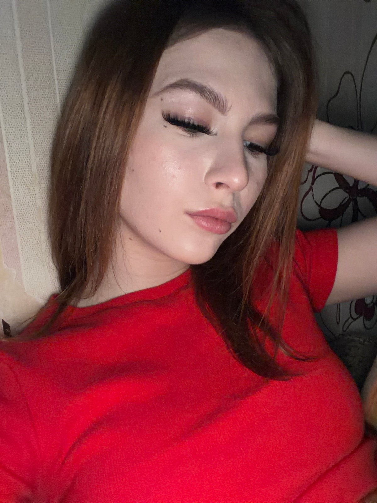 Woman in red top resting indoors in Noviy, Russia