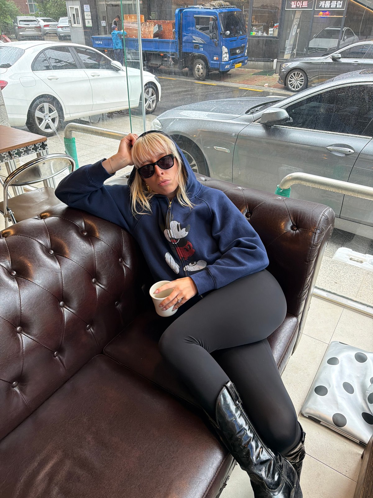 Woman in Mickey Mouse hoodie rests in Seoul cafe