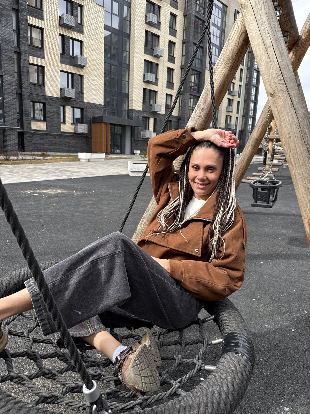 Woman enjoys playground swing in Rusanovo park
