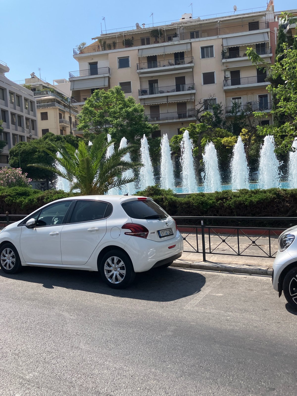 Urban street scene with parked Peugeot and roadside sculpture