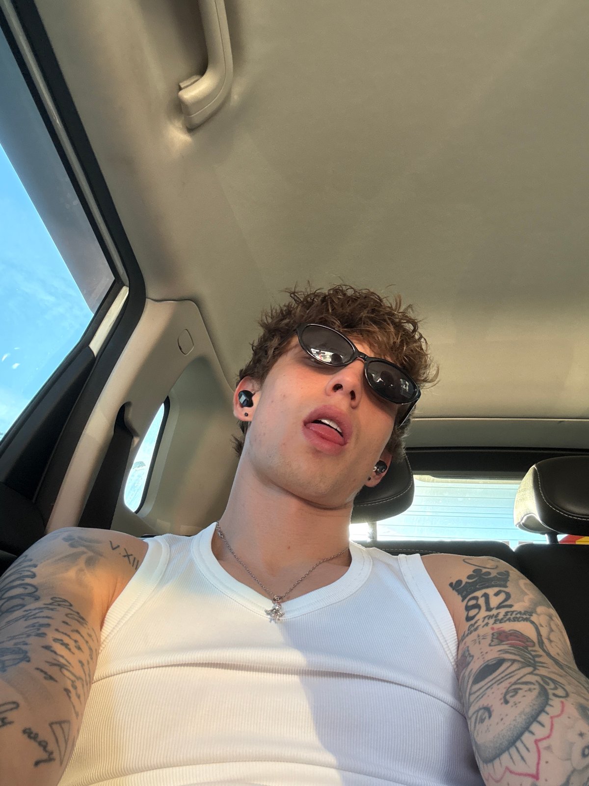 Tattooed man in white tank top observed in car