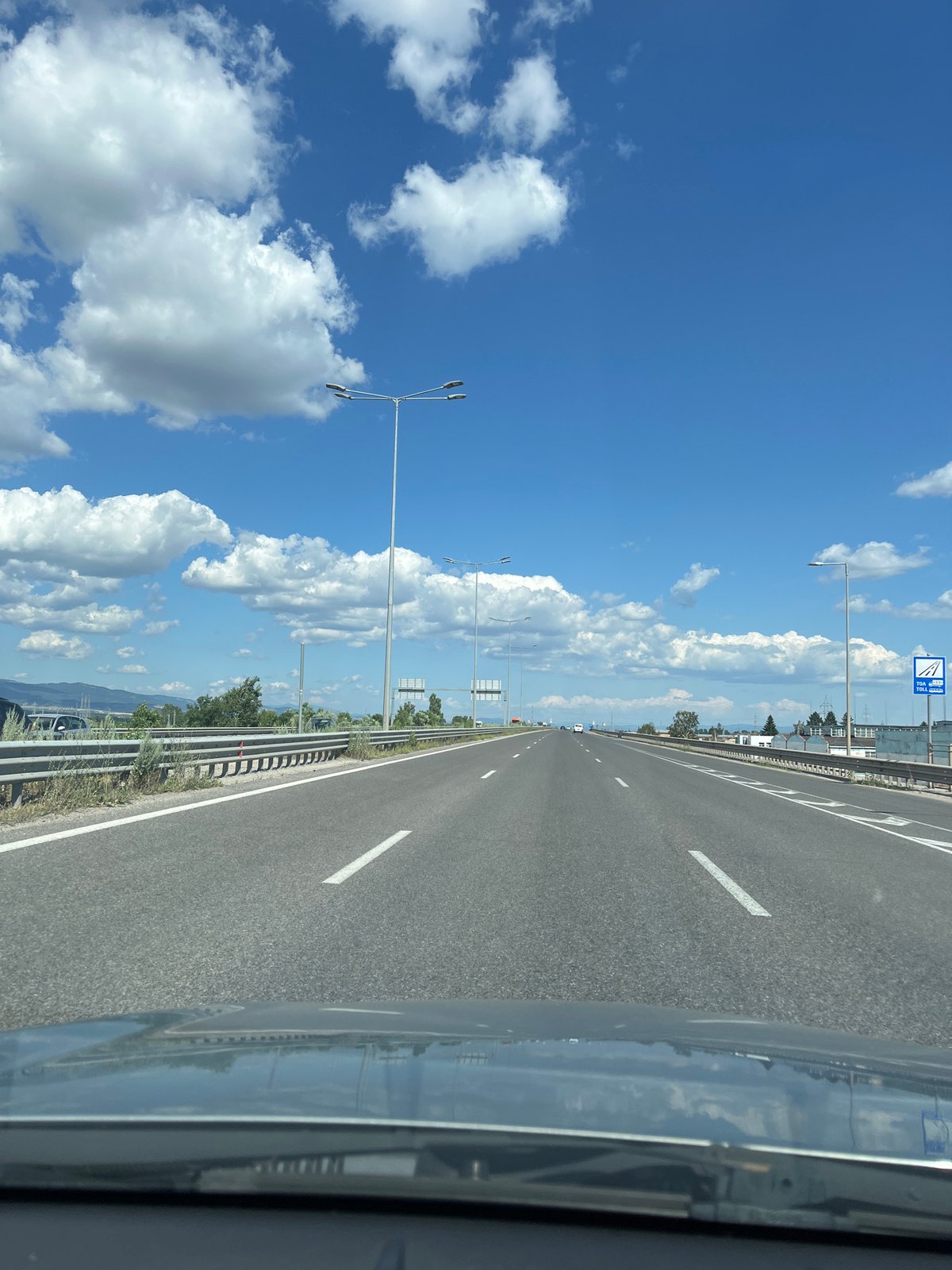 Sunny highway drive through mountainous landscape under blue skies