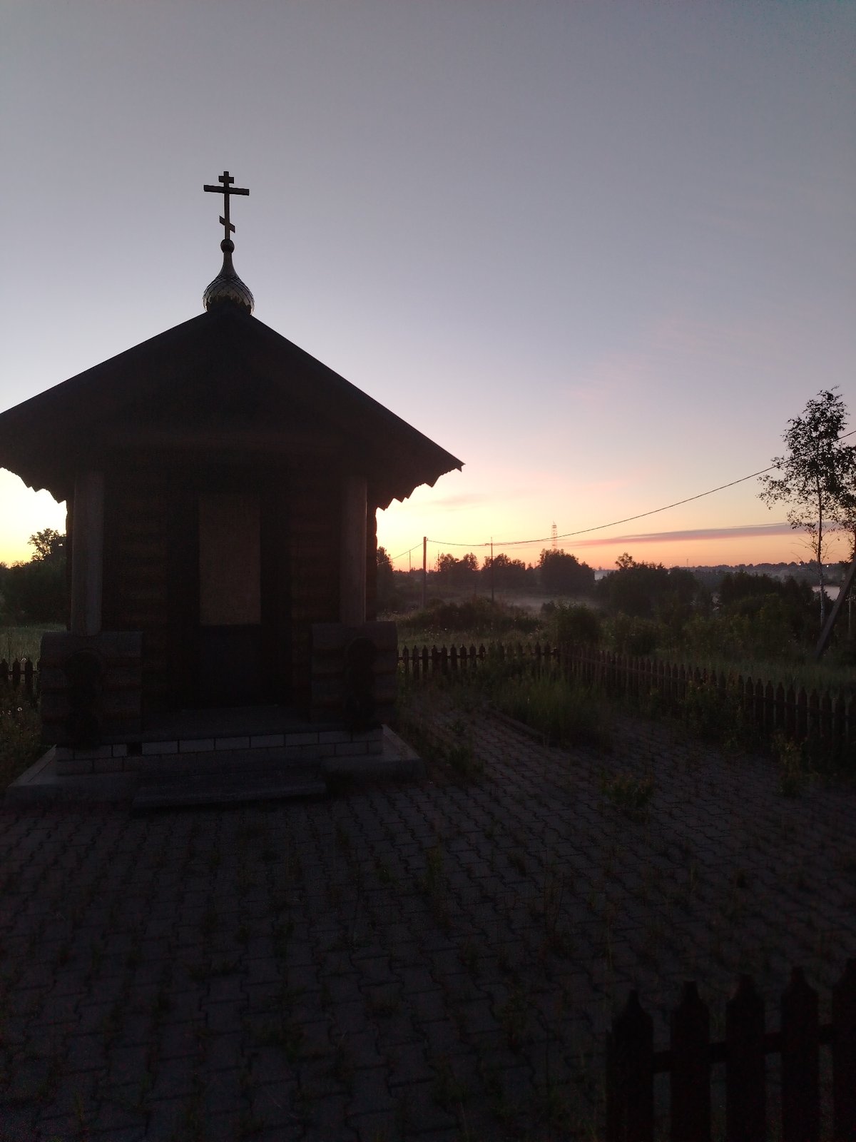 Dawn captures wooden chapel, rural crossroads in Petrovskoye, Russia