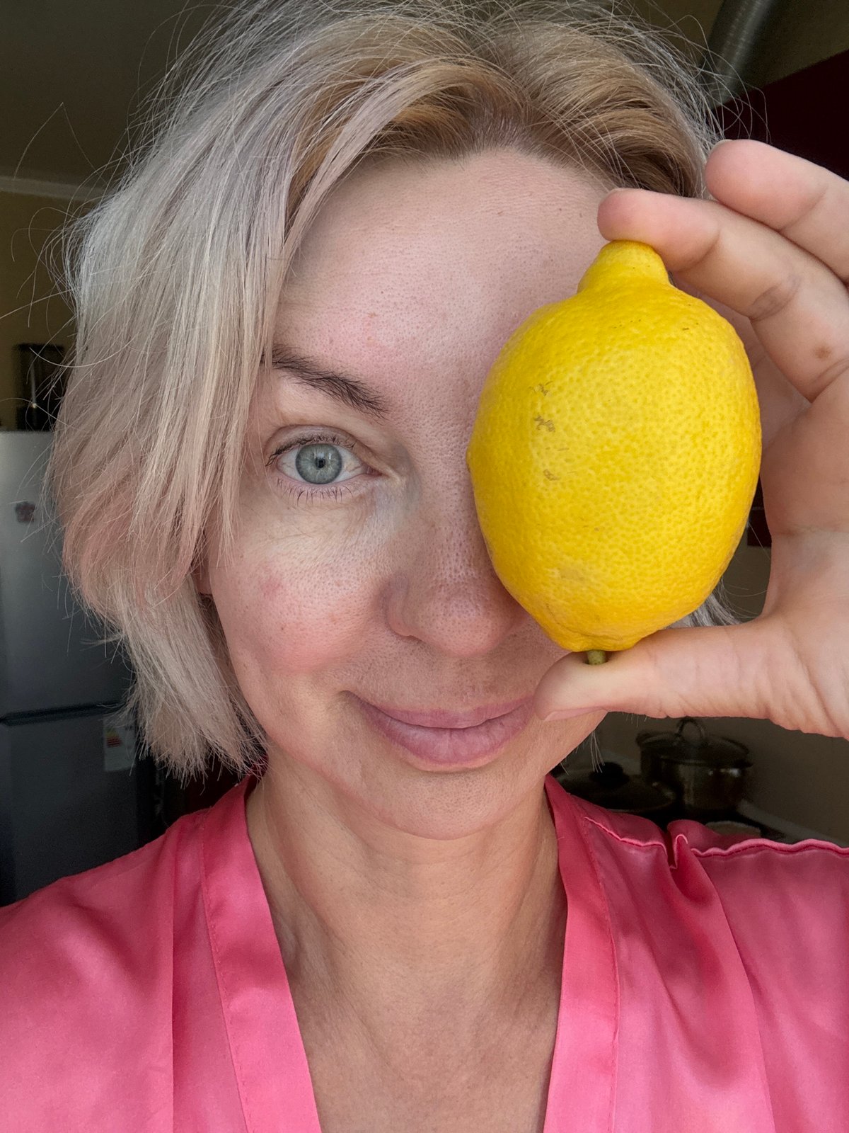 Lemon held to eye, pink robe, direct camera gaze in Sochi