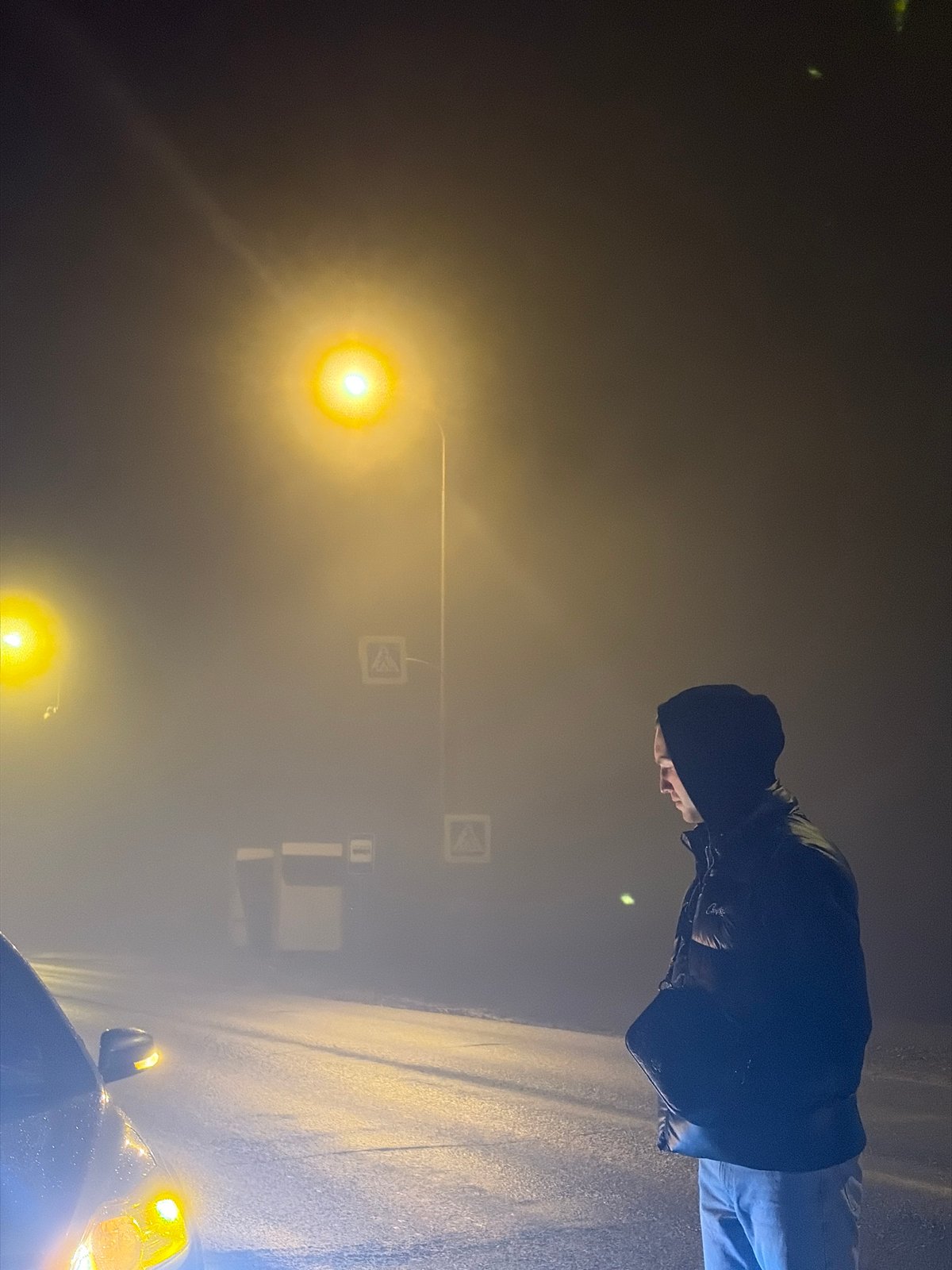 Man stands beside car on foggy Russian road