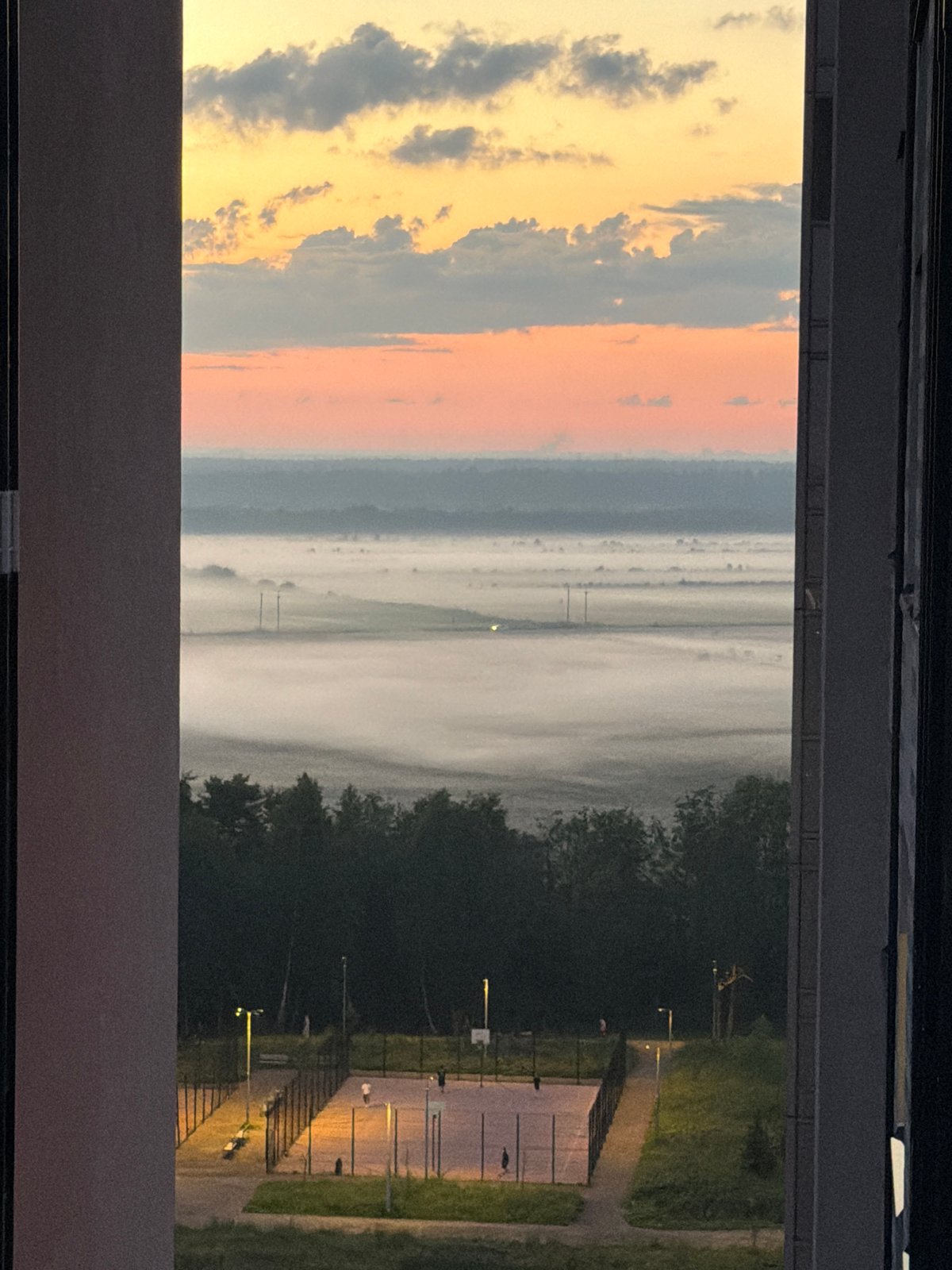 Indoor window frame looking out at a dusk landscape