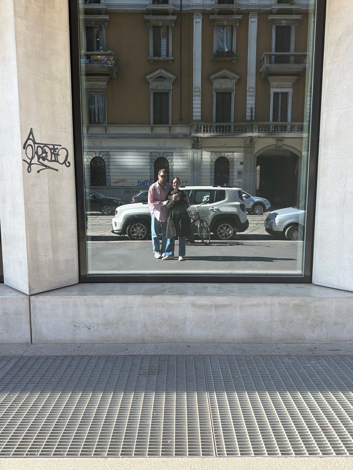 Reflective building window mirrors street scene in Milan