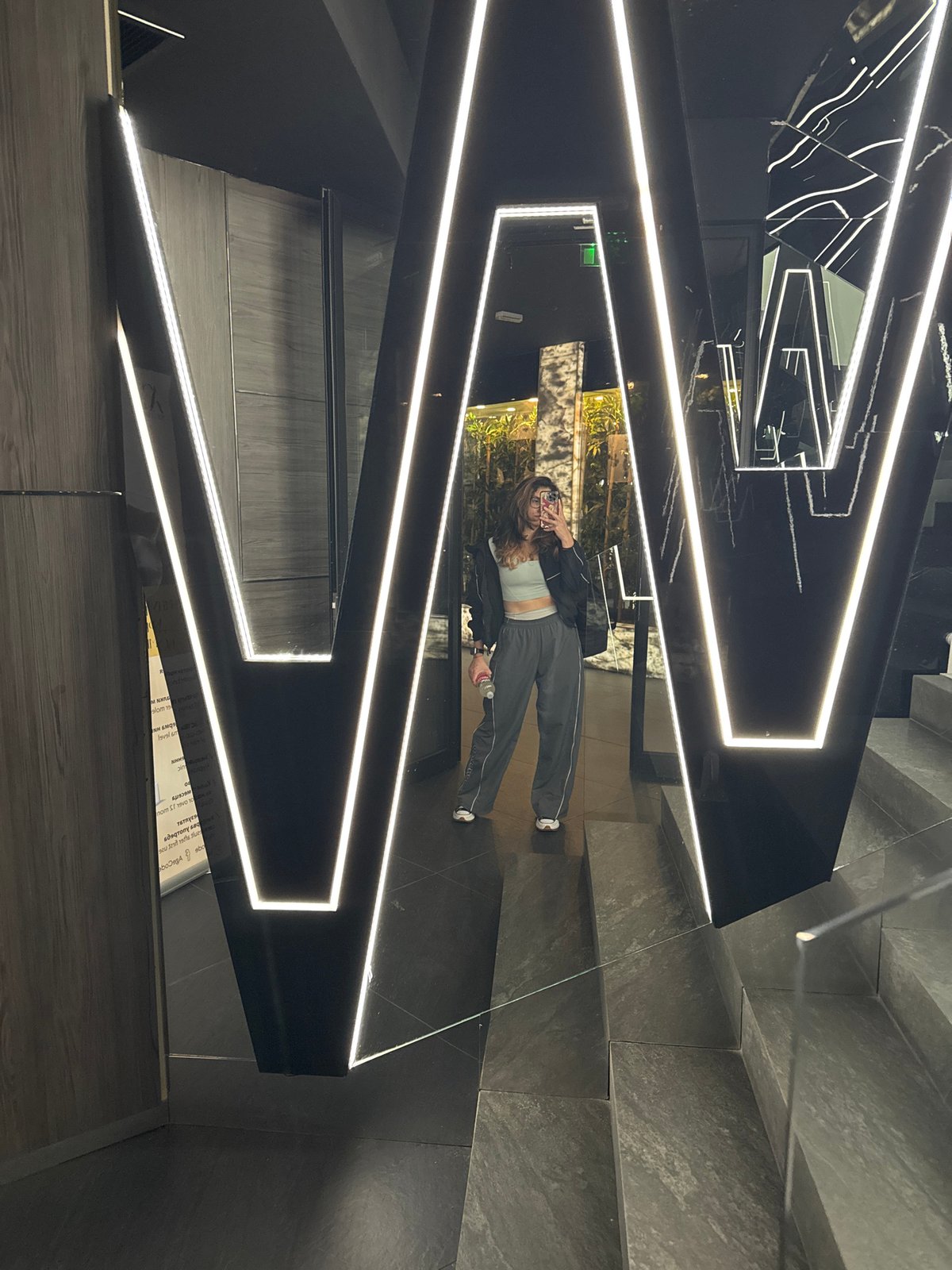 Woman takes mirror selfie in modern reflective interior space