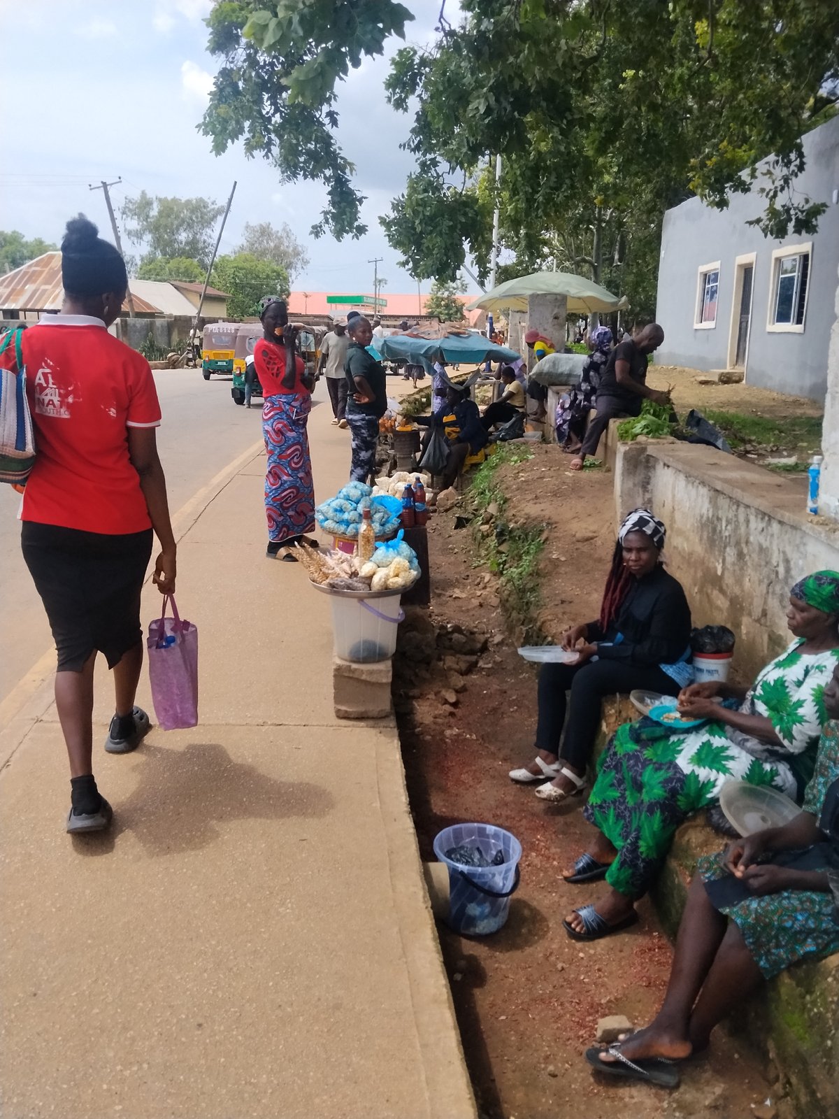 Street life along a busy Jos road on a cloudy afternoon