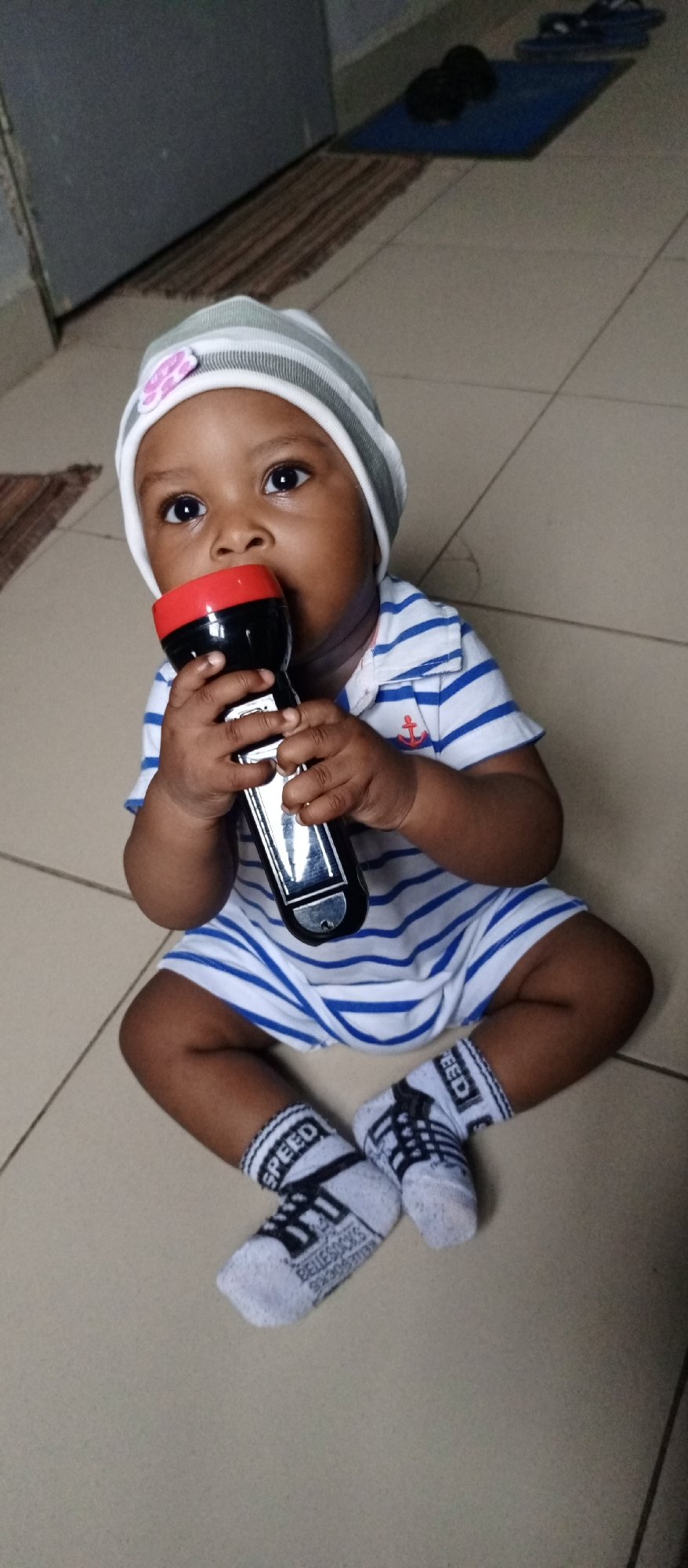 Baby in striped outfit observed with flashlight across indoor locations