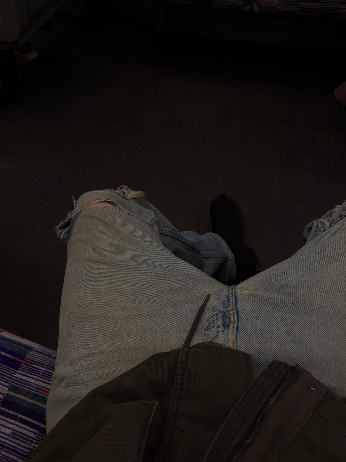 Person in ripped jeans observed seated indoors in London