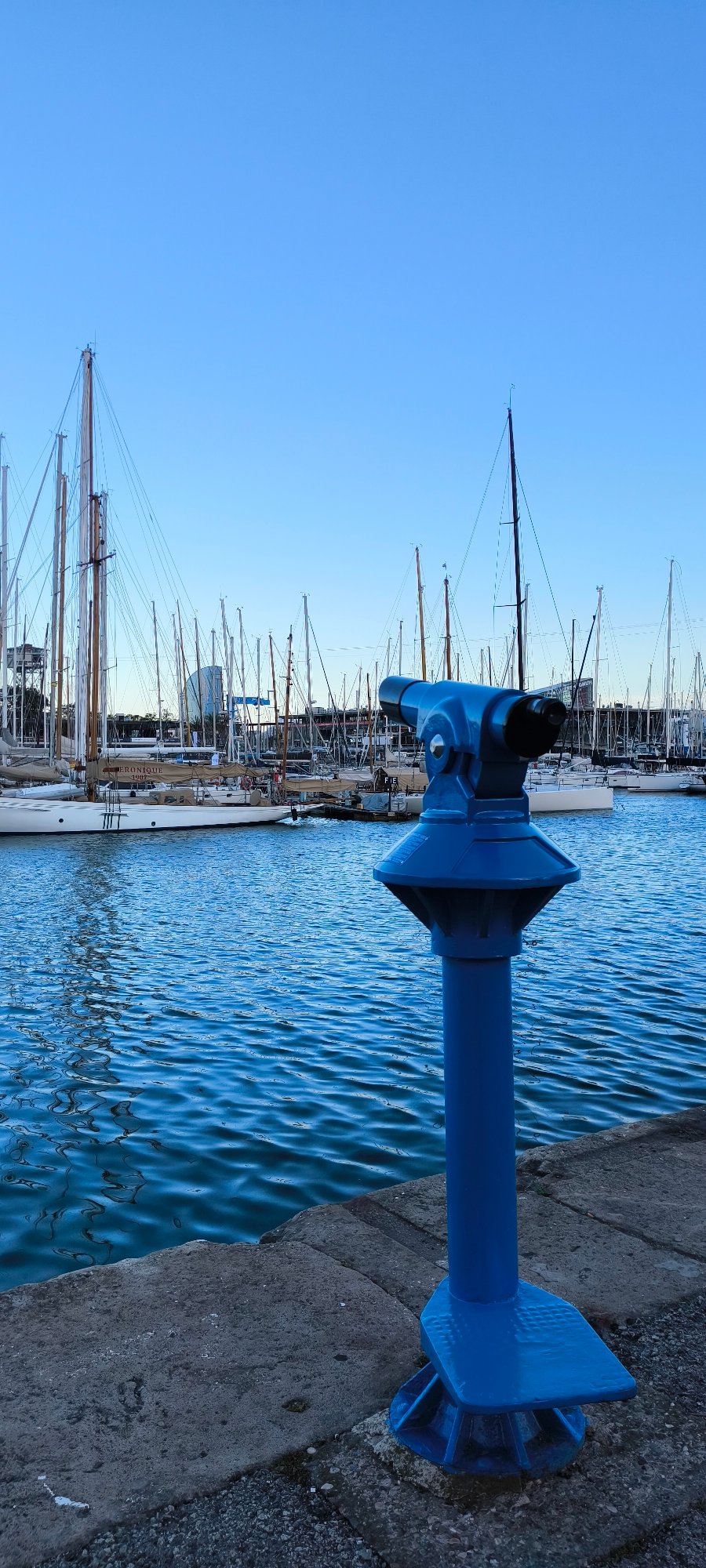 Coin telescope overlooks marina with docked boats under clear skies