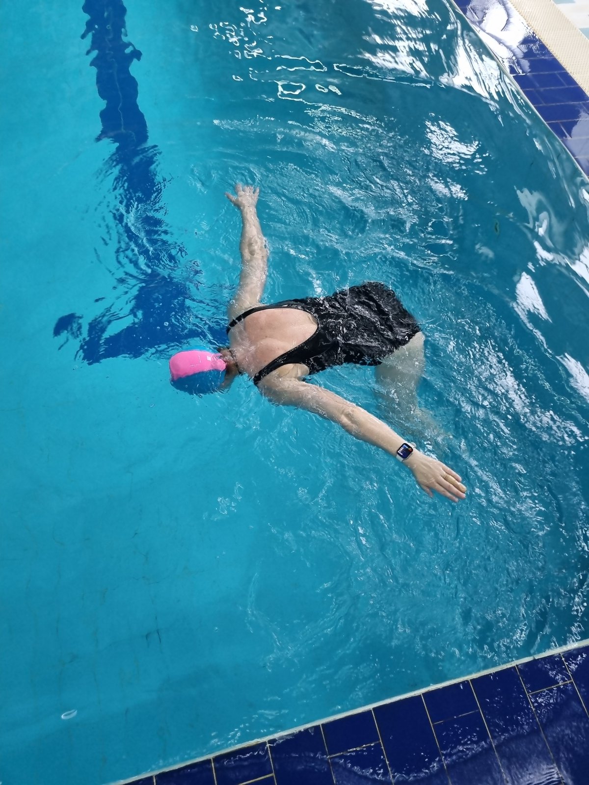 Swimmer performs breaststroke in pool during early morning hours