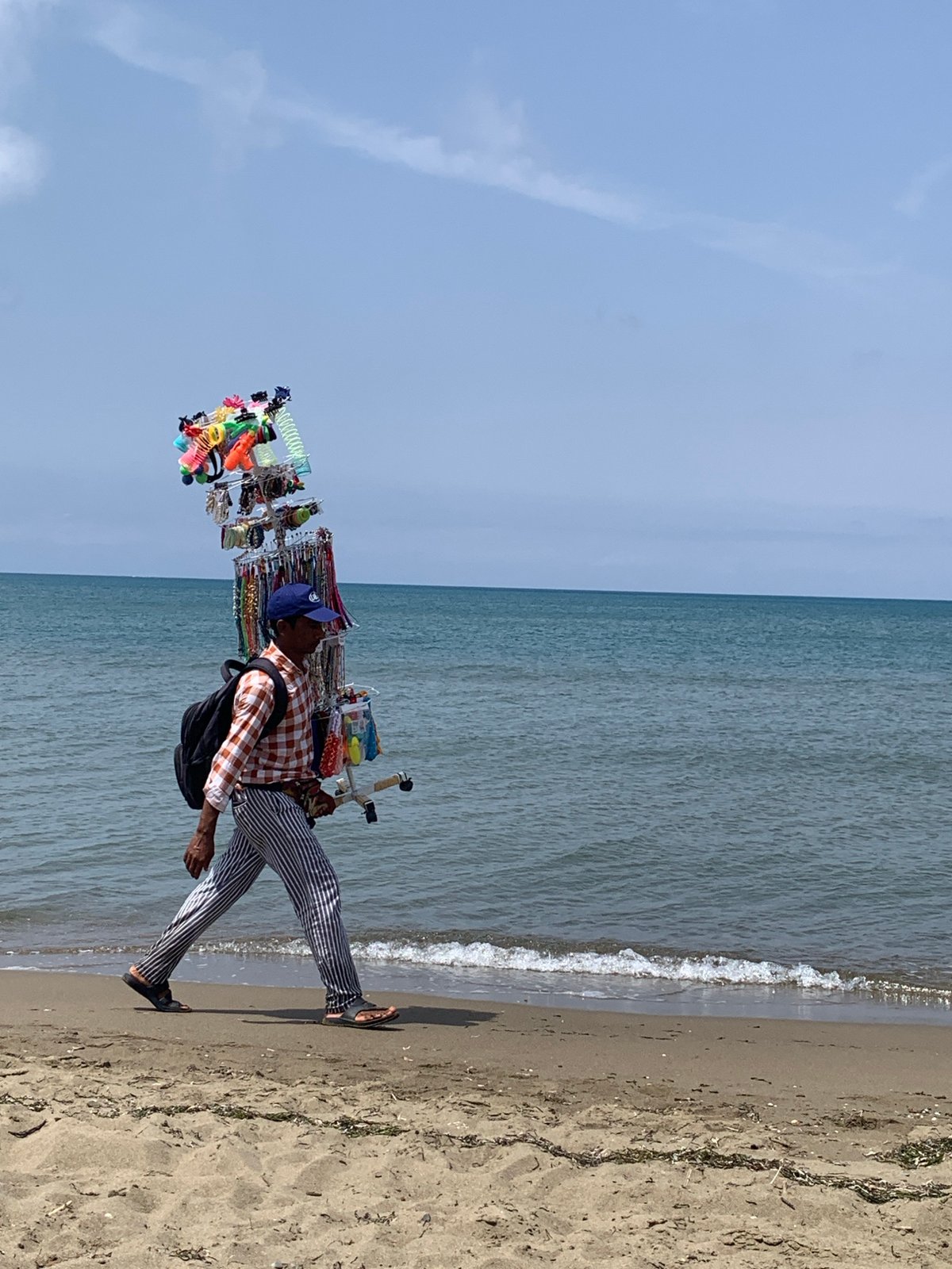 Beach vendor and morning strollers along Orbetello's shoreline