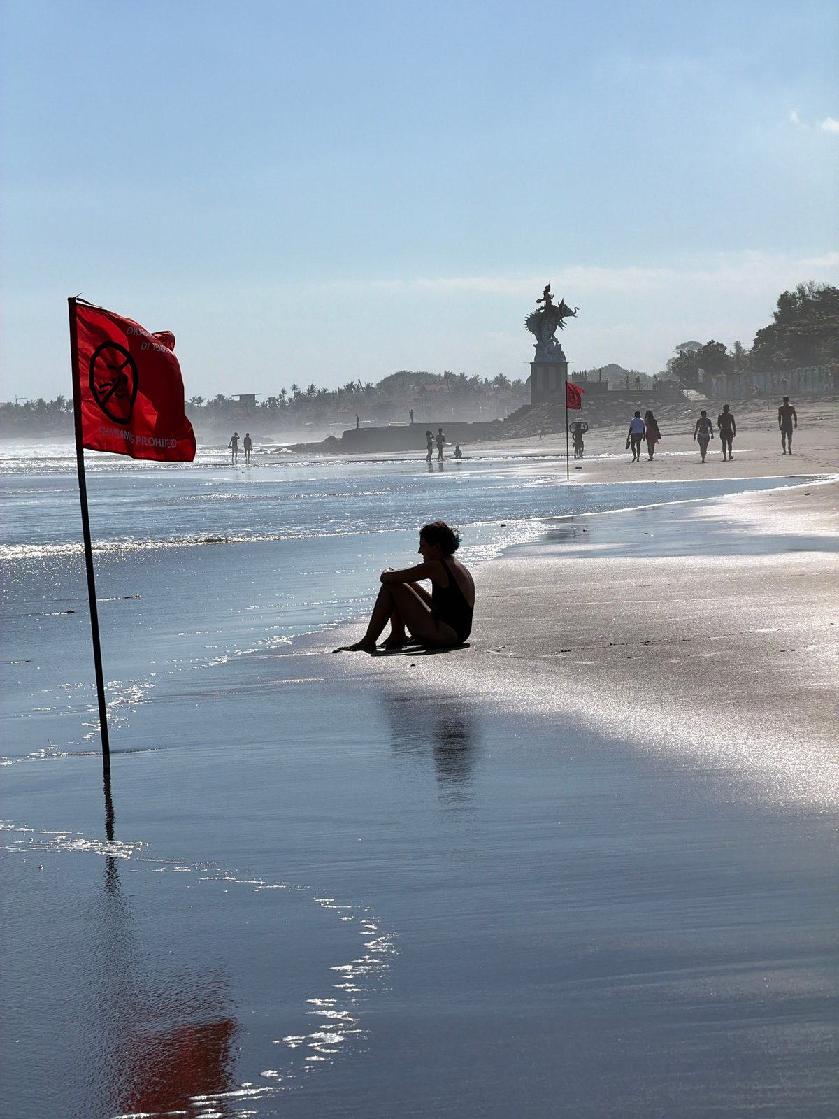 Morning at a flagged beach on Bali's volcanic sand coast