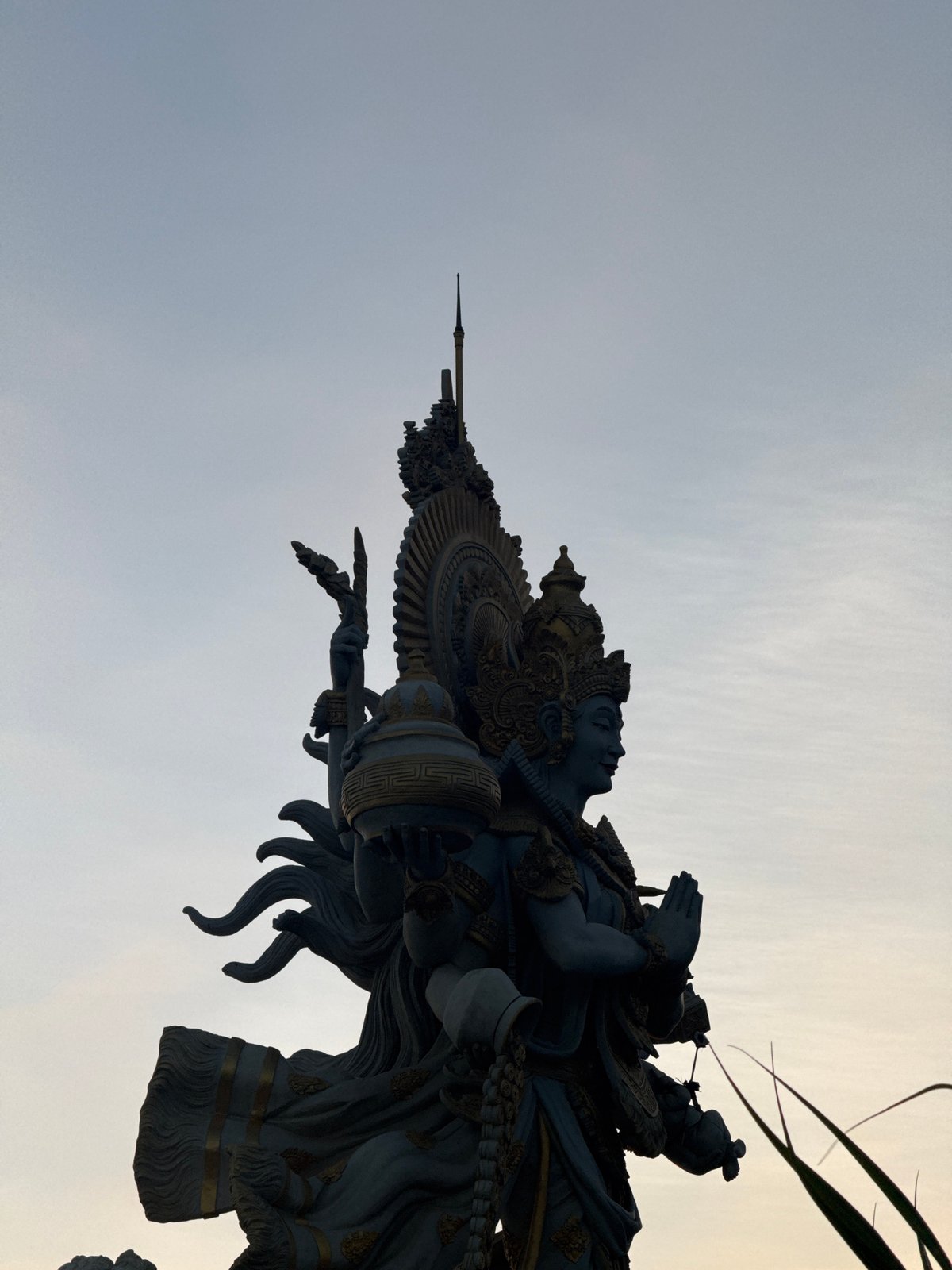 Busy Kuta Beach at sunset — vendors, crowds, and a deity statue