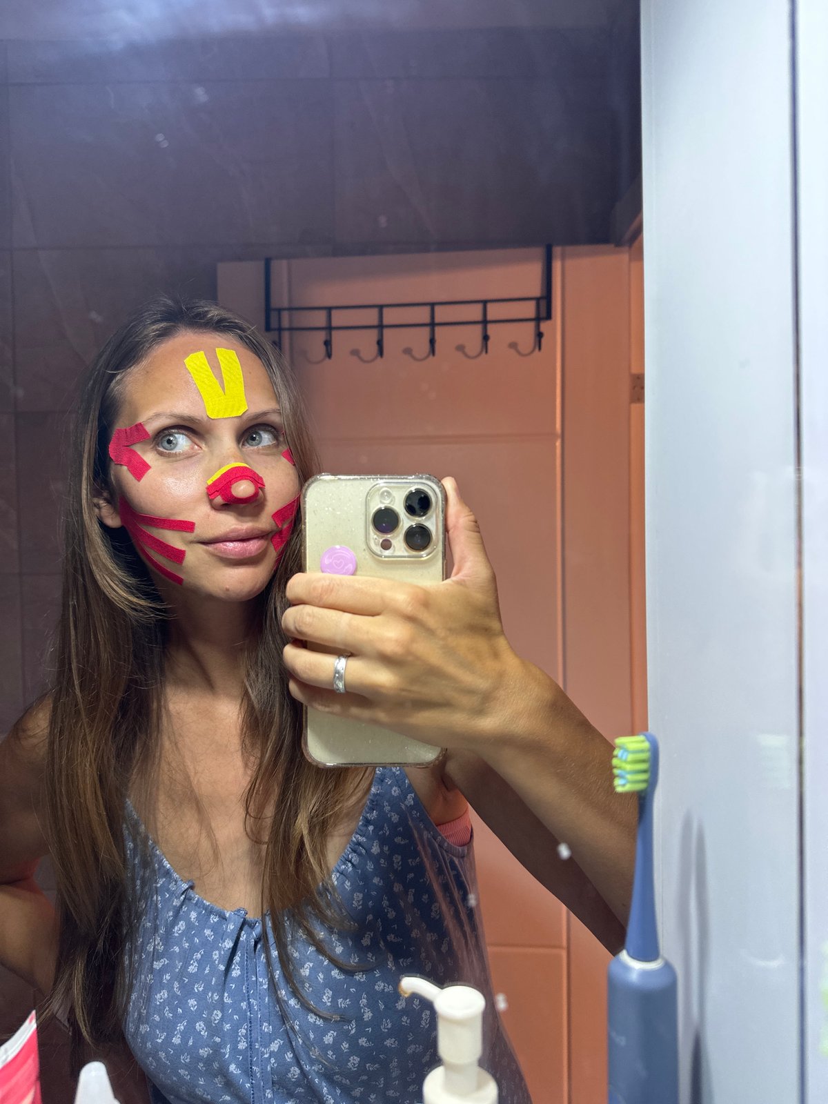 Woman applies colorful tape to face in Turkish bathroom