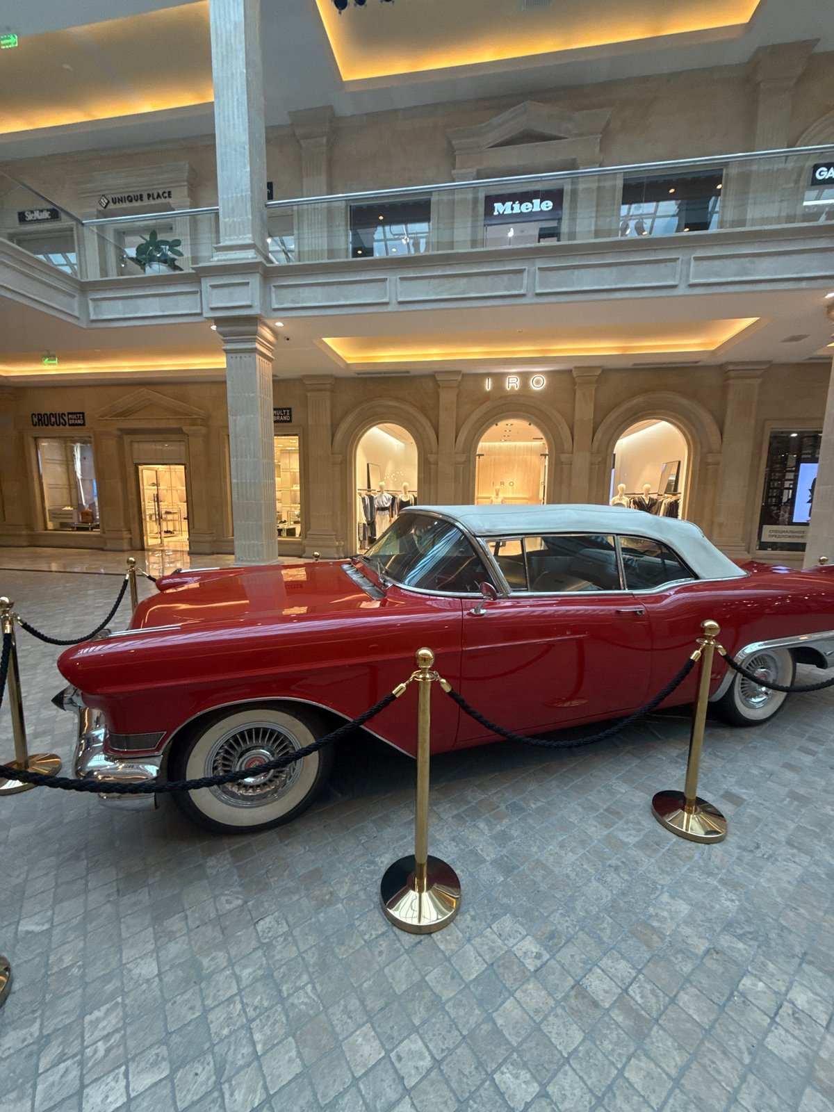 Vintage red Cadillac on display inside a grand indoor atrium