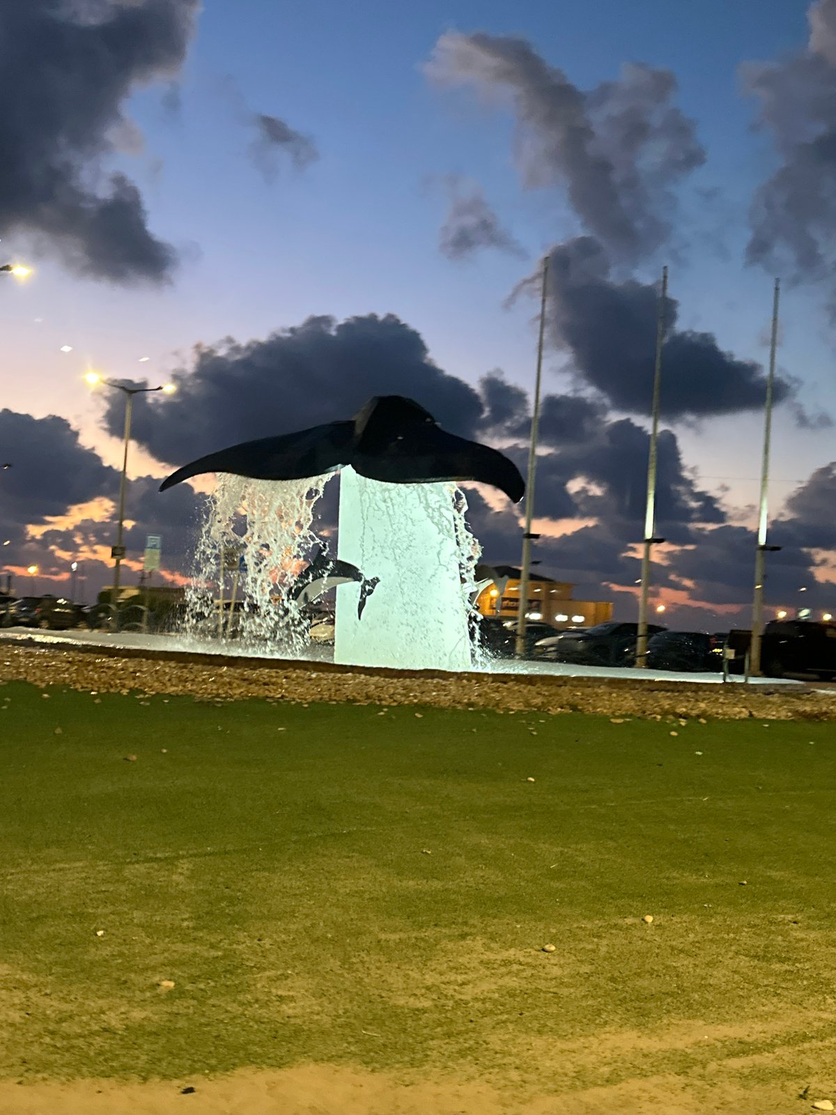 Kiryat Yam waterfront at dusk: sculptures, dining, and lit archways