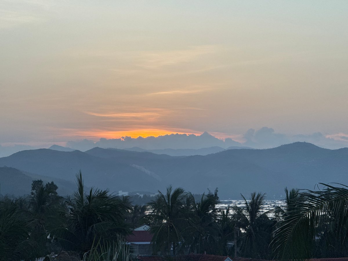 Sunset over Song Cau's coastline, palms and mountains in silhouette