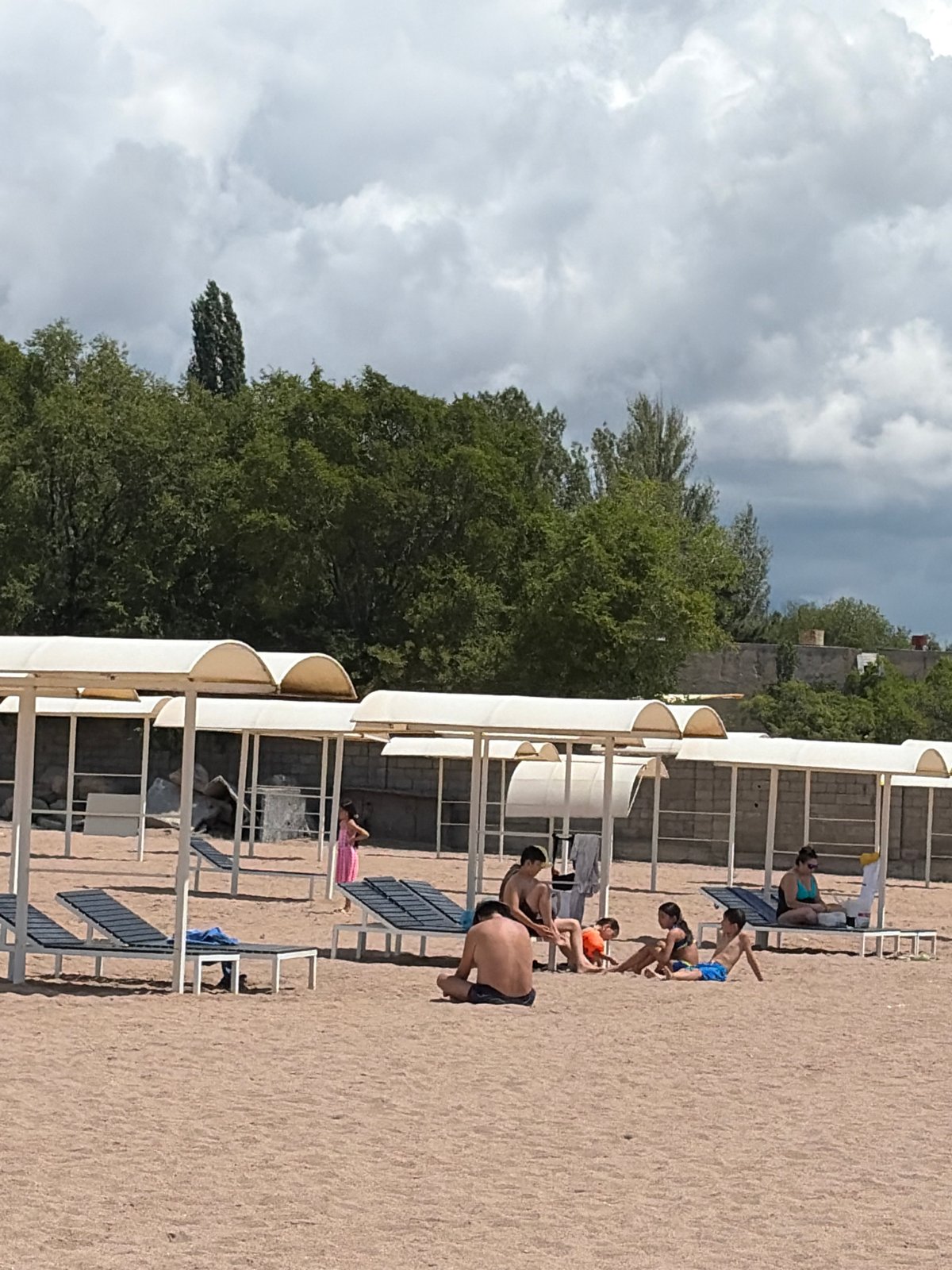 Relaxed beach day at a pier with calm water and canopies