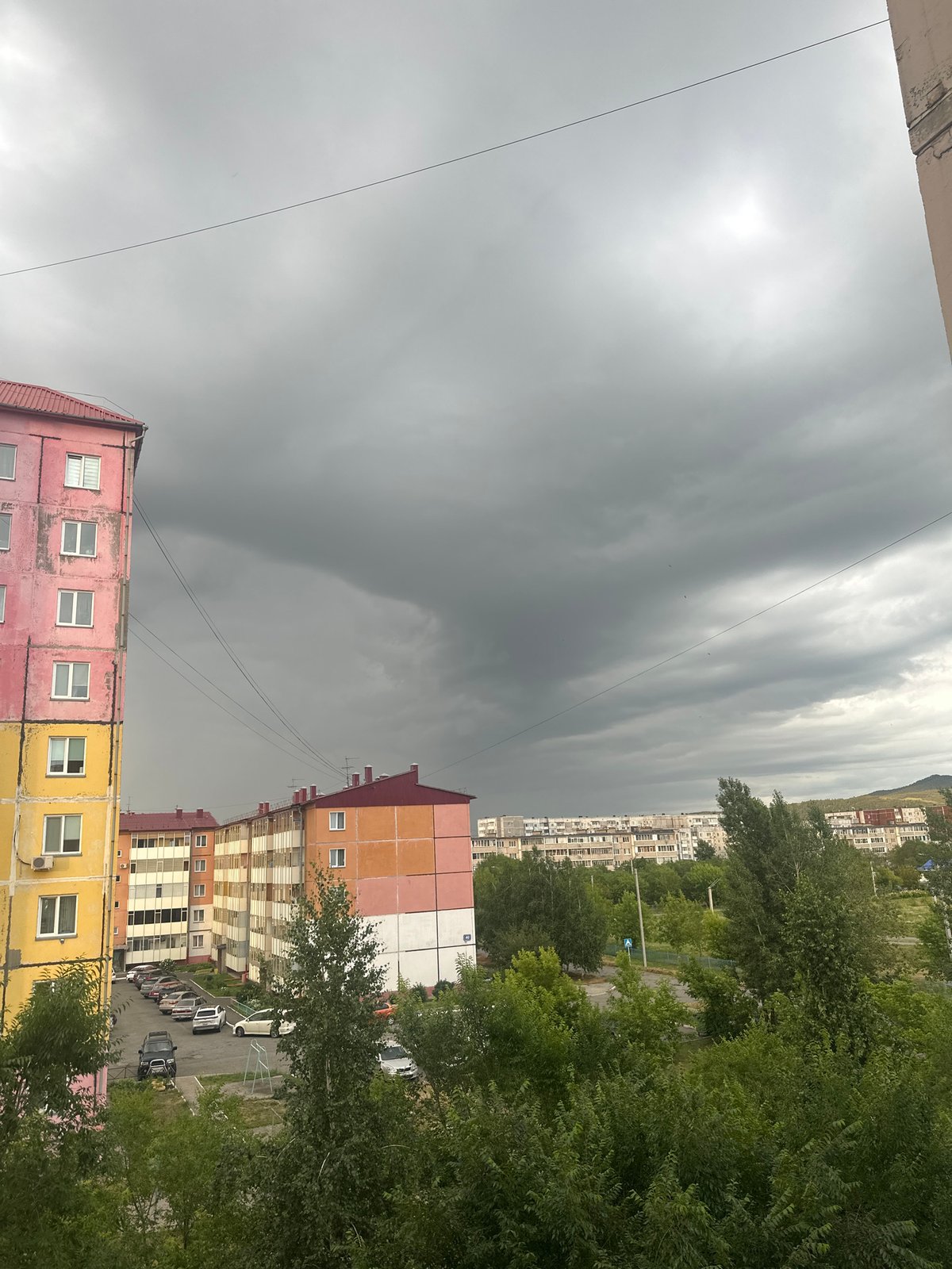 Storm clouds over Sayanogorsk apartments, with a gold-chained dog inside