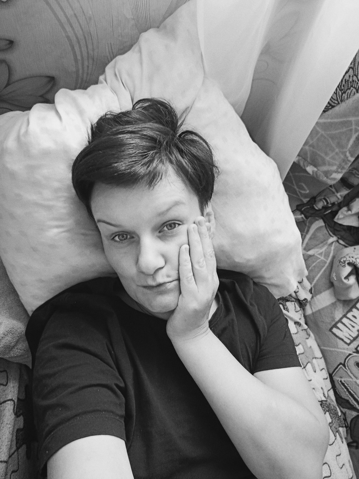 Close overhead black and white shot, lying on a bed, direct gaze.