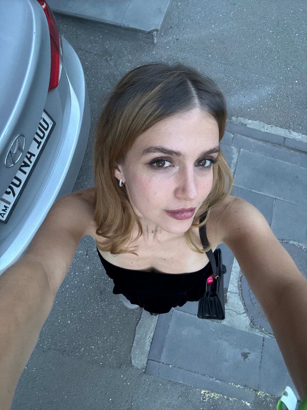 Woman takes selfie near silver car in Yerevan