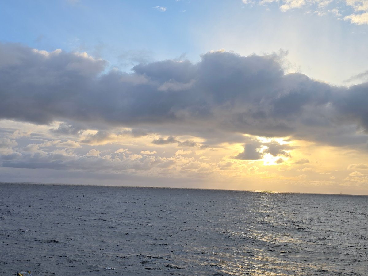 Ocean sunset observed under cloudy skies with warm reflections