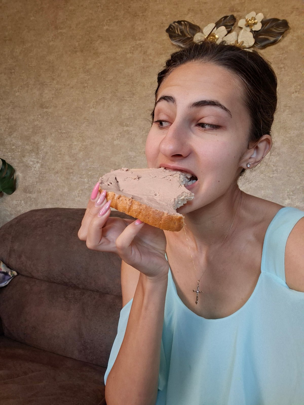 Indoors on a couch, mid-bite into a pâté-topped slice of bread.