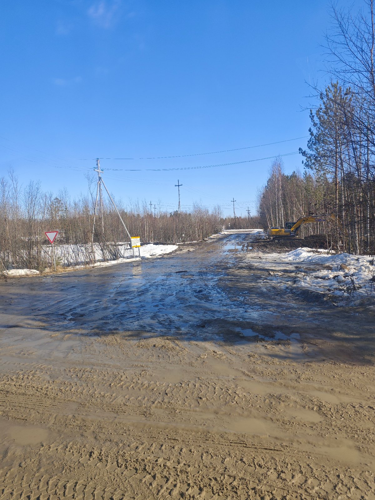 Muddy flooded road with excavator and car in rural Russia