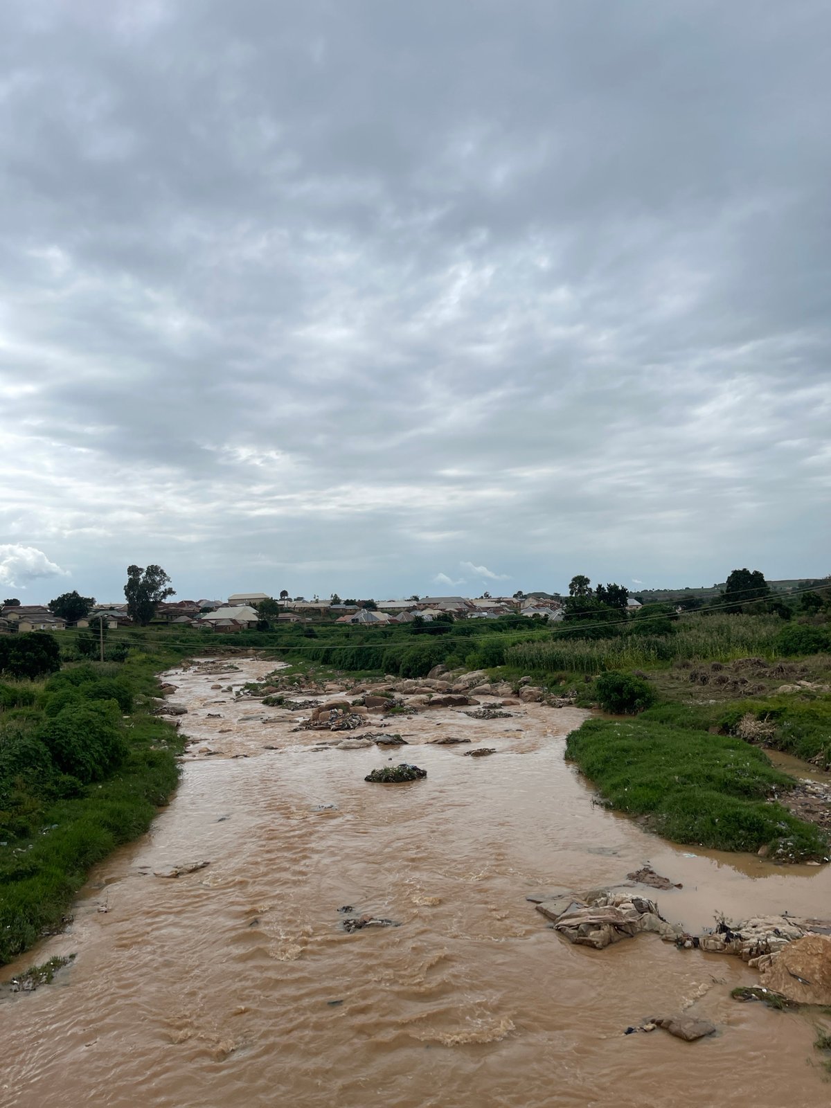 Group crosses bridge over polluted river in Rafin Par, Nigeria
