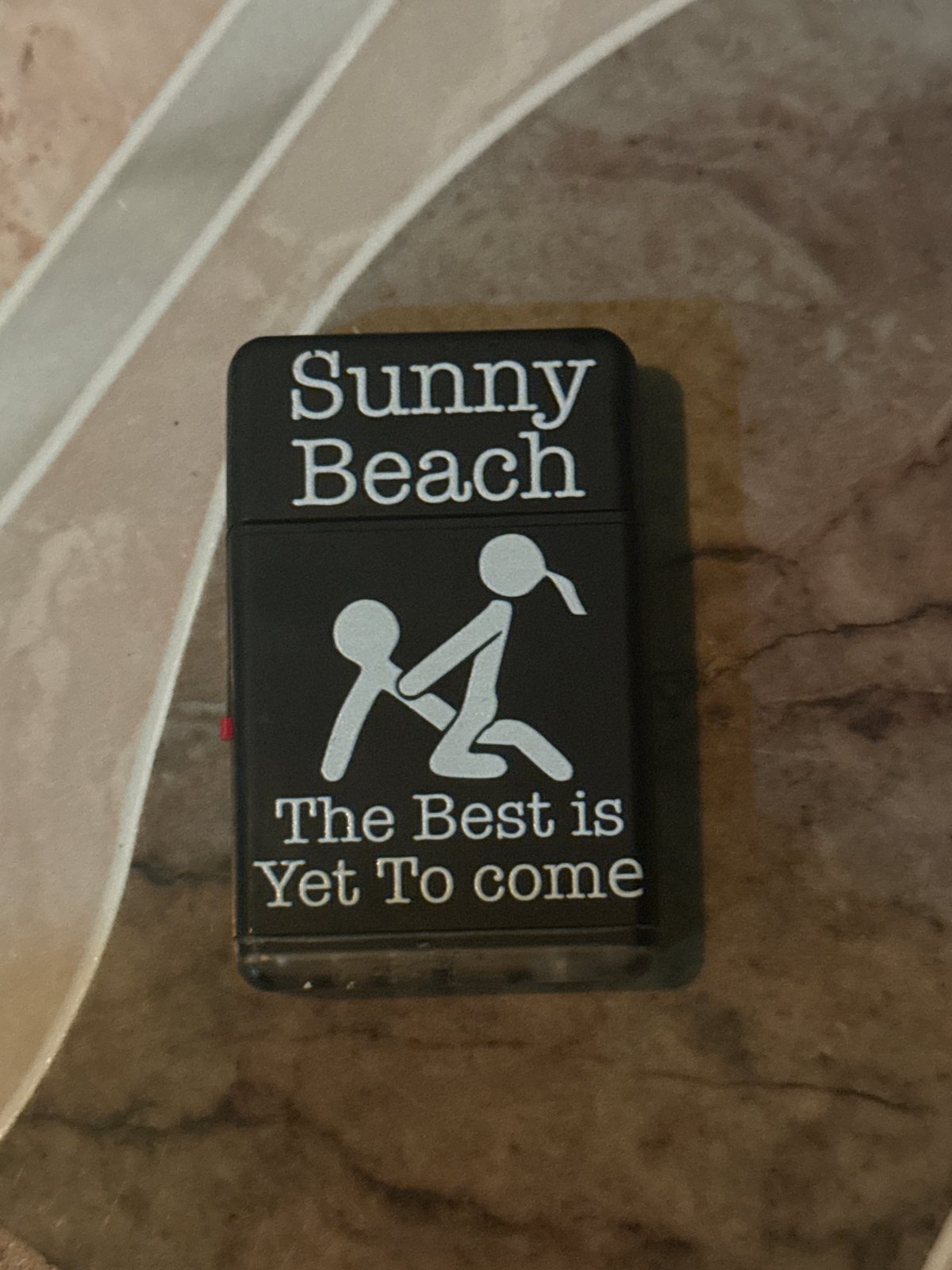 Sunny Beach branded Zippo lighter observed on marbled surface