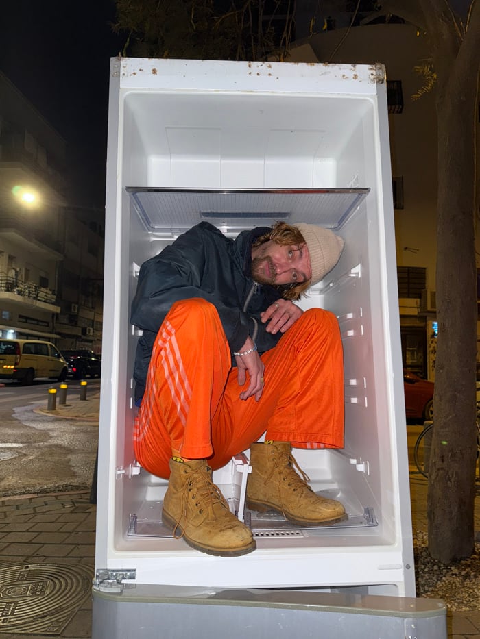 Person sits in outdoor refrigerator on Tel Aviv street