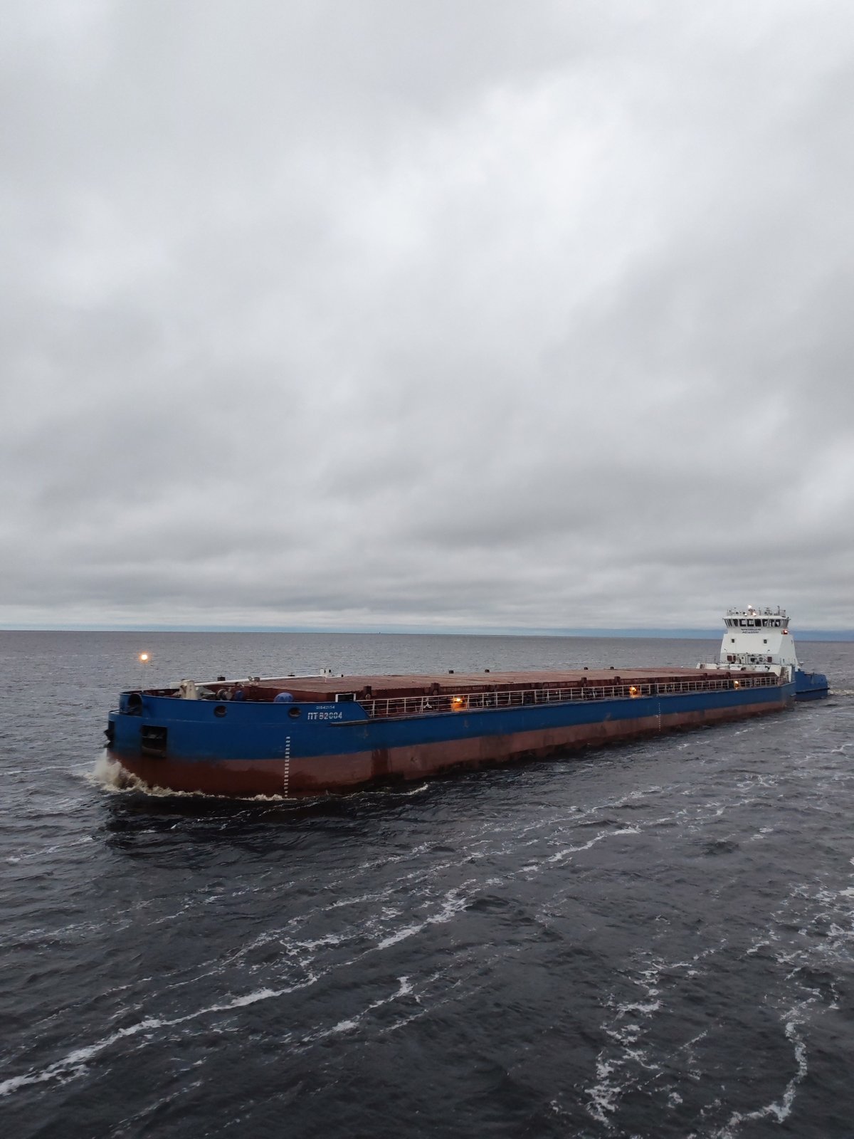 Tugboat pushes barge through choppy waters near Bereg, Russia