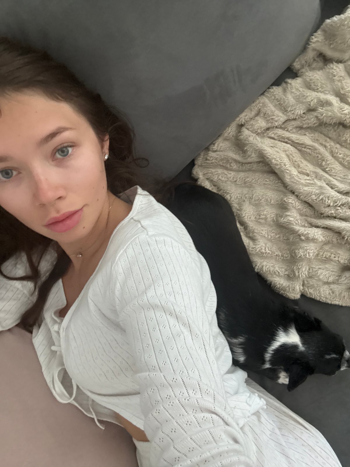 Woman and dog rest together on sofa in Ramat Gan